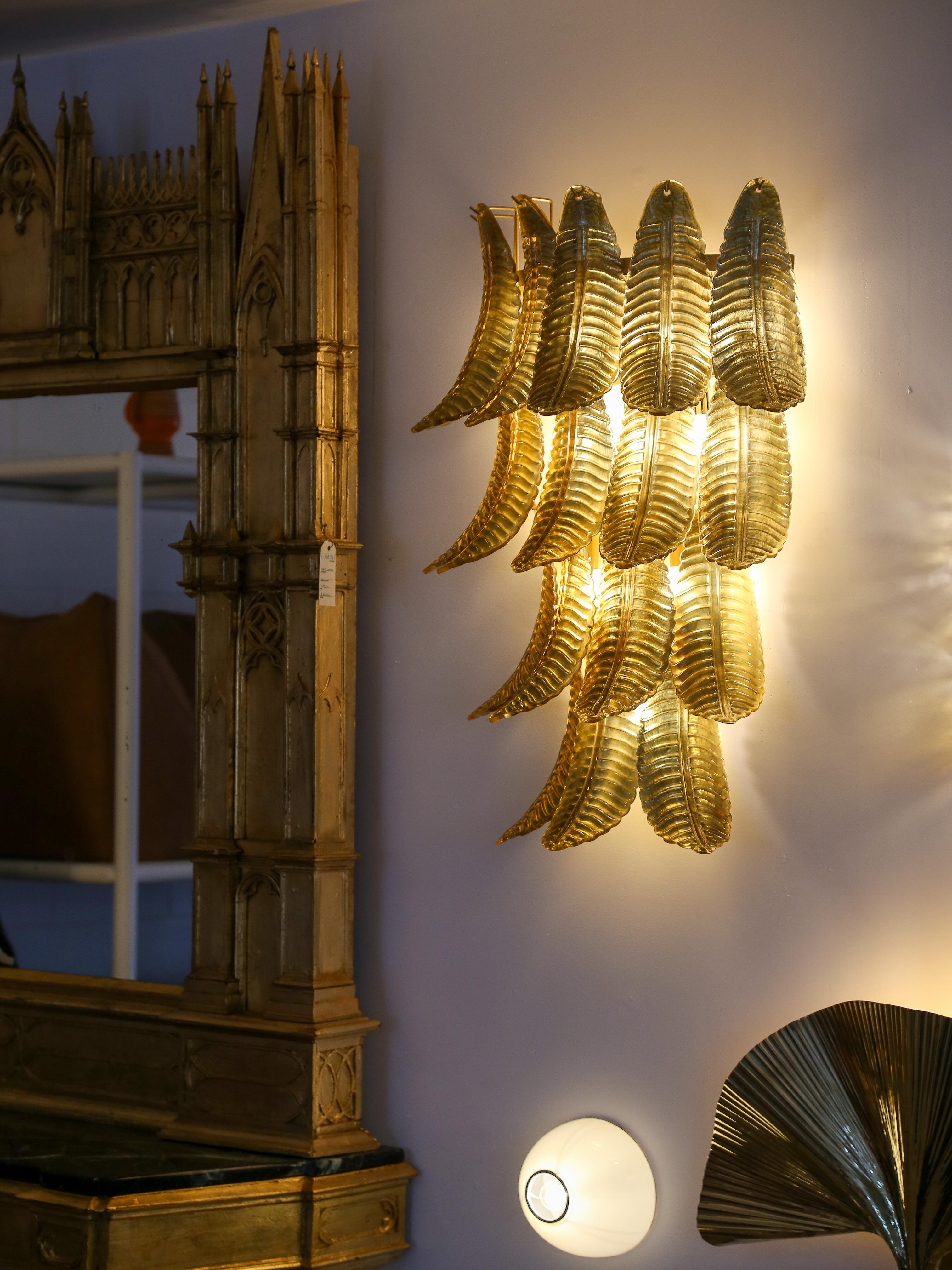 This stunning sconce is composed of a large set of Murano gold glass leaves positioned all around a brass structure. The leaves are positioned on four levels, the first at the top has six leaves, the second four leaves, third level has four elements