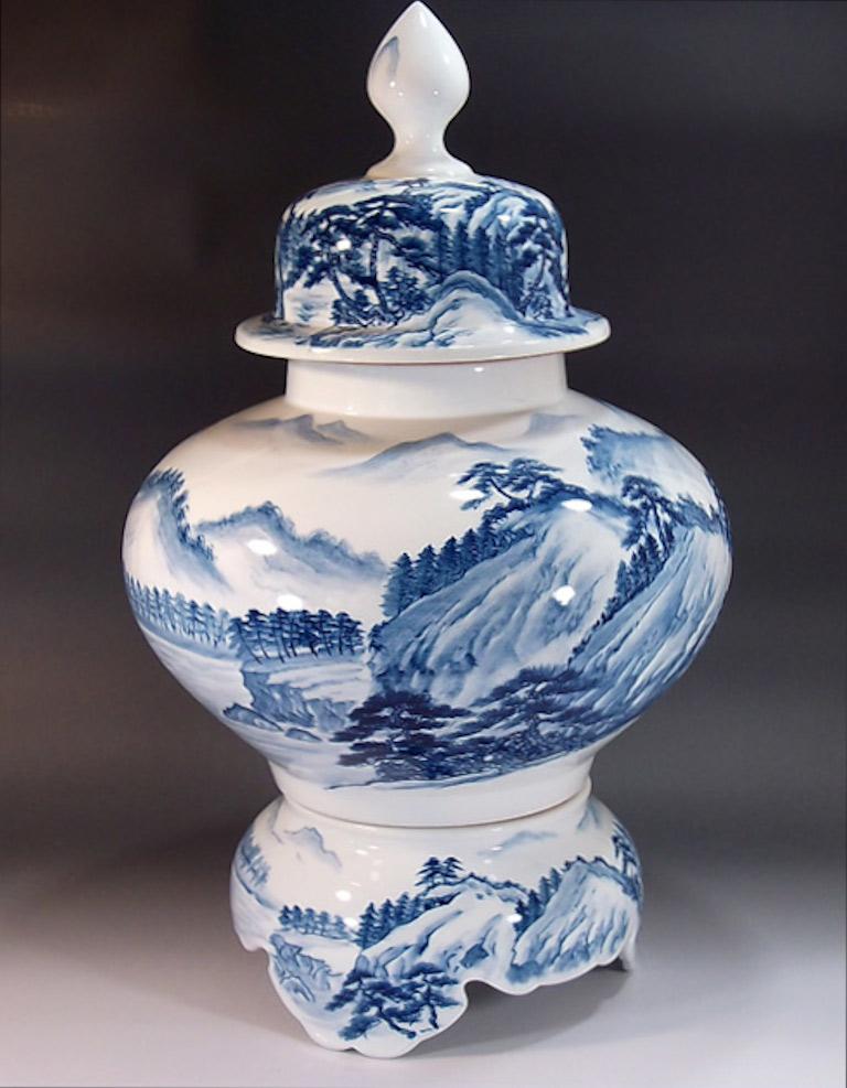 Exquisite very large contemporary Japanese porcelain decorative three-piece raised lidded jar, hand painted in underglaze blue and white , depicting a landscape from Japan's countryside , a signed work by widely acclaimed Japanese master porcelain