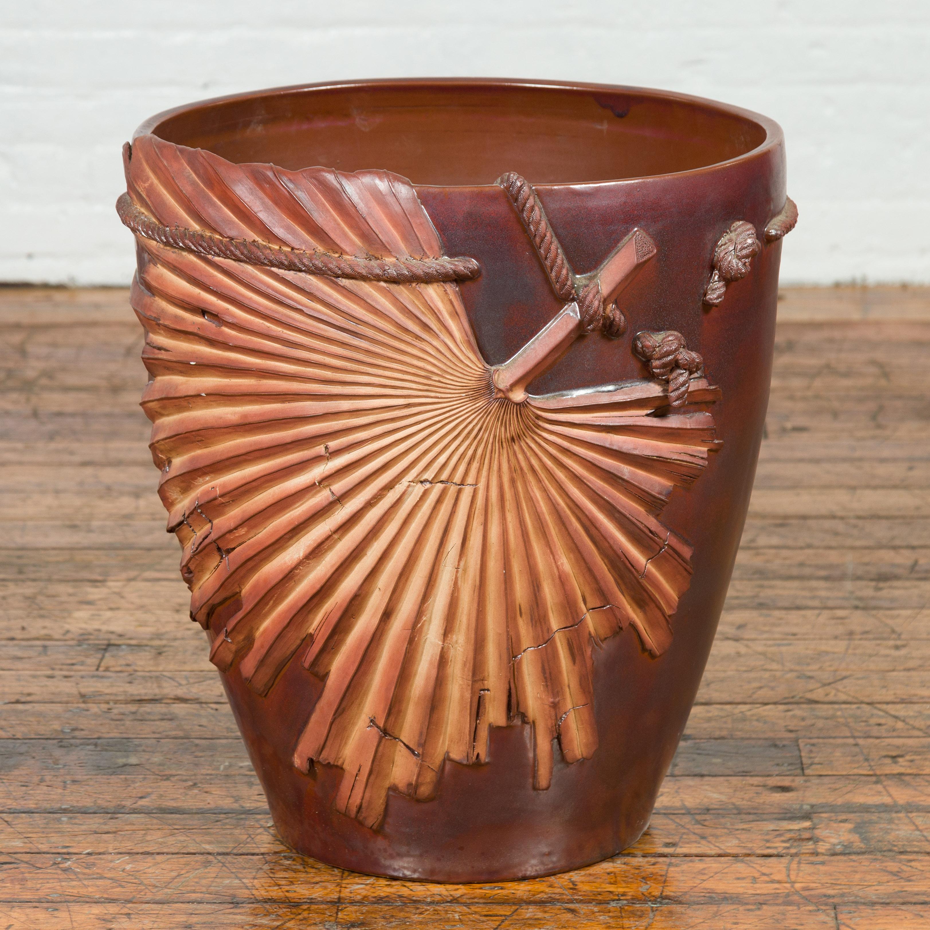 A large contemporary Thai garnet toned planter with palm leaf and rope motifs. We currently have two available, priced and sold individually (1,300 each). Look at image #3 to see them together. Created in Thailand, this large planter will draw the