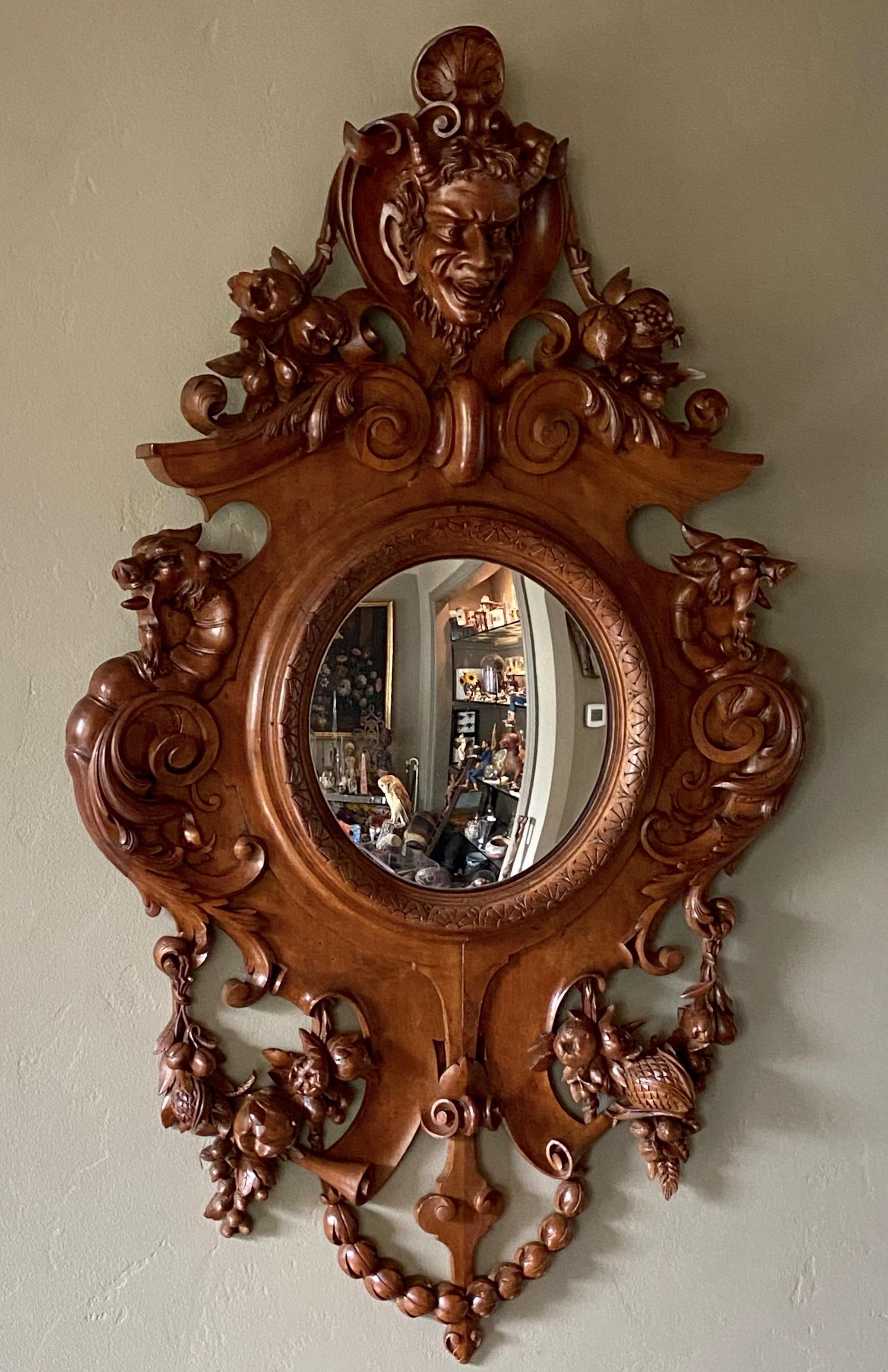 An impressive large scale elaborately carved walnut convex mirror.
Wonderful detailed carving of mythical Pan or Satyr at the top pediment, surrounded with swags of fruits and nuts and wolf heads on either side.
Continental / European late 19th