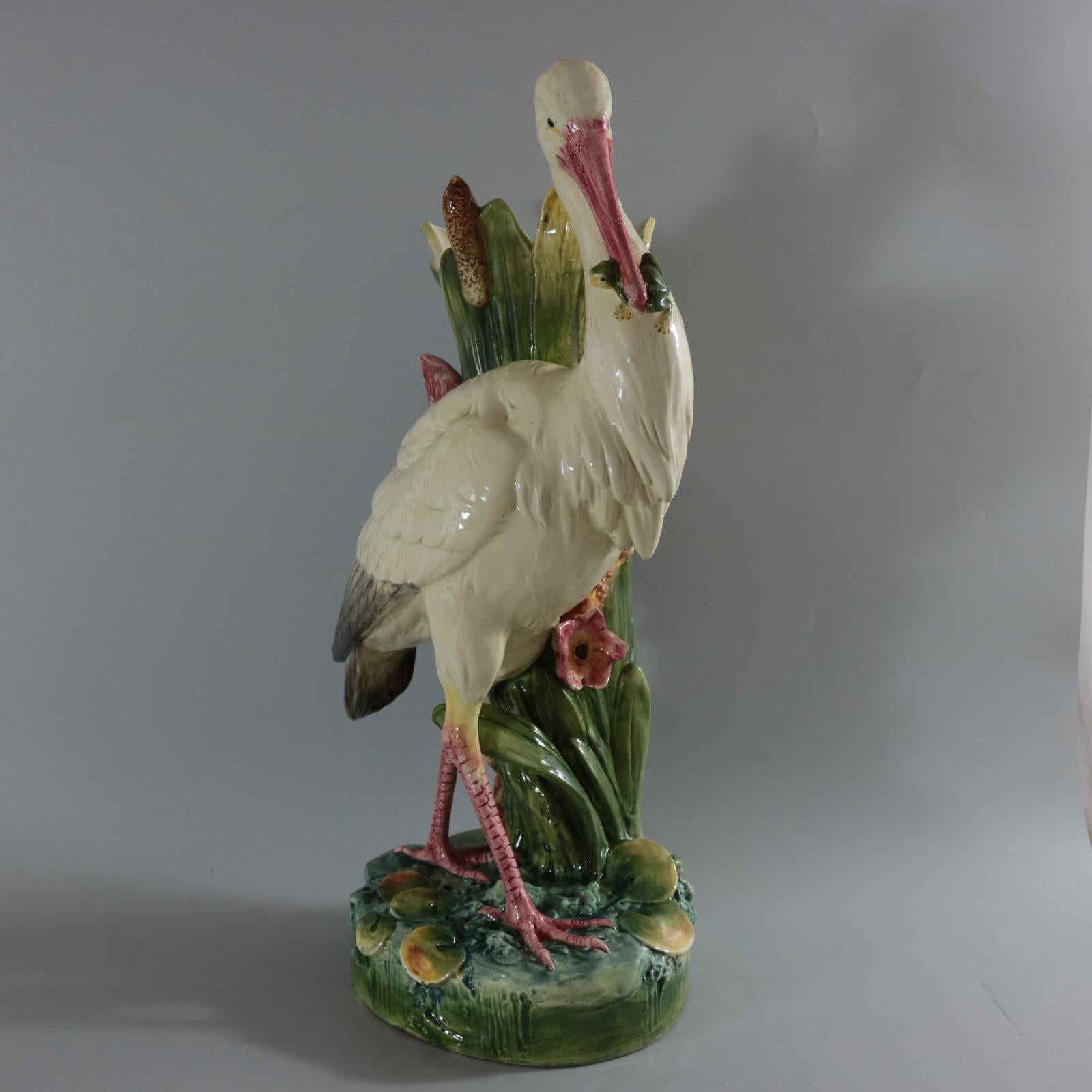 Unidentified Czechoslovakian Majolica figural vase which features a stork with a frog in it's beak, stood amongst lilies and bullrushes/cattails. Colouration: white, green, pink, are predominant. Bears an unidentified maker's mark, 'Made in
