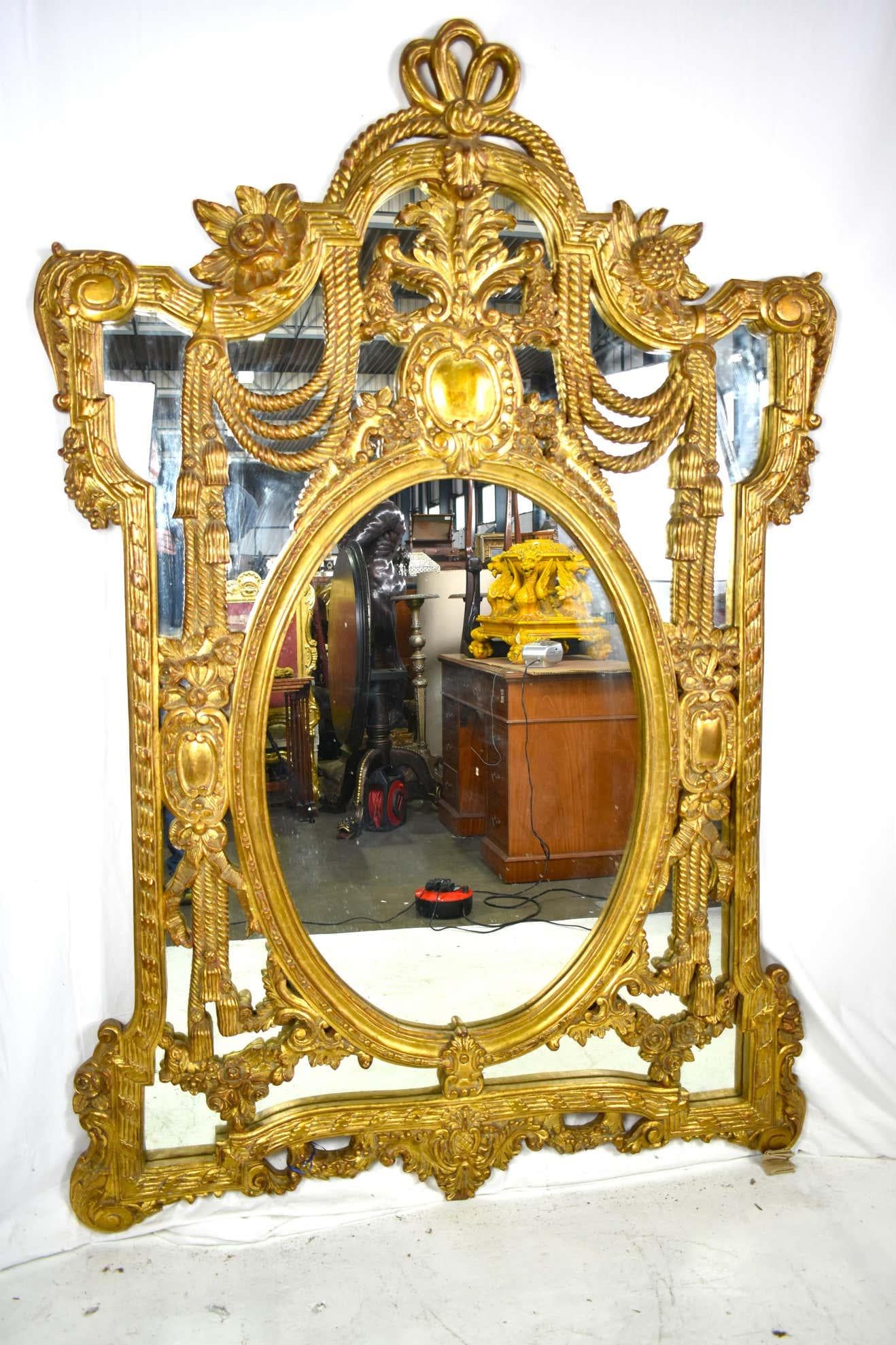 Un grand et impressionnant miroir ancien avec un cadre orné de dorures et fortement décoré avec une exceptionnelle crête sculptée de rinceaux et de feuillages, surmontant un miroir flanqué de bordures torsadées et chantournées.