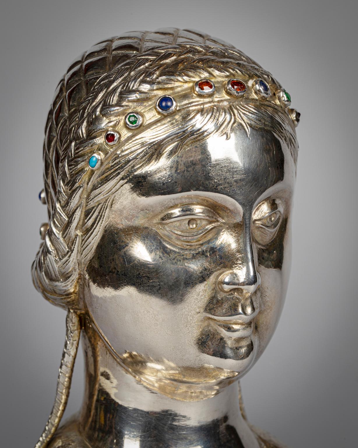 The female figure in Medieval dress, her braided hair drawn back from in her into a chignon, the three quarter bust opening to reveal the coffret, set with jewels and semi precious stones.
