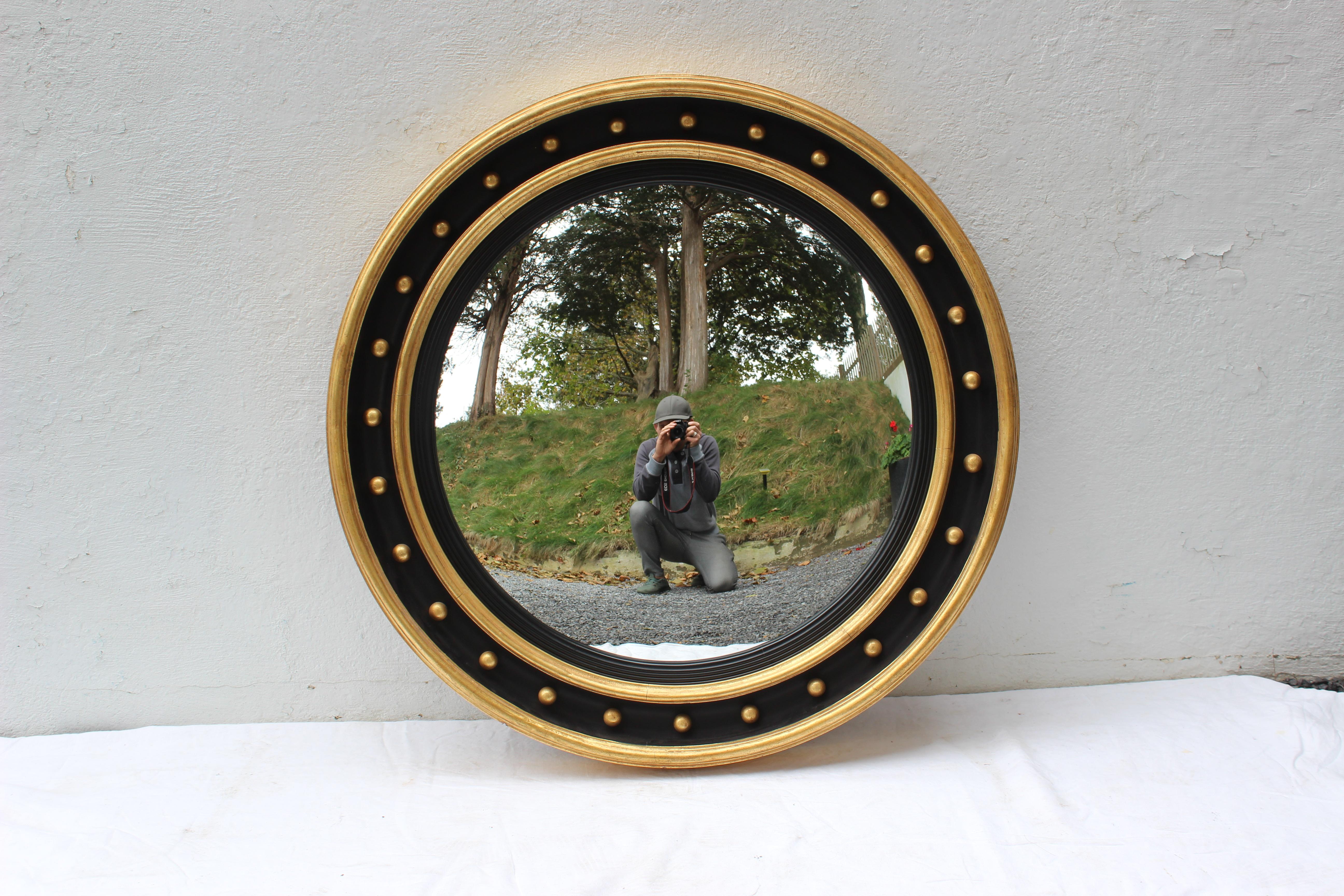 Large black and gold framed mirror with convex glass.
