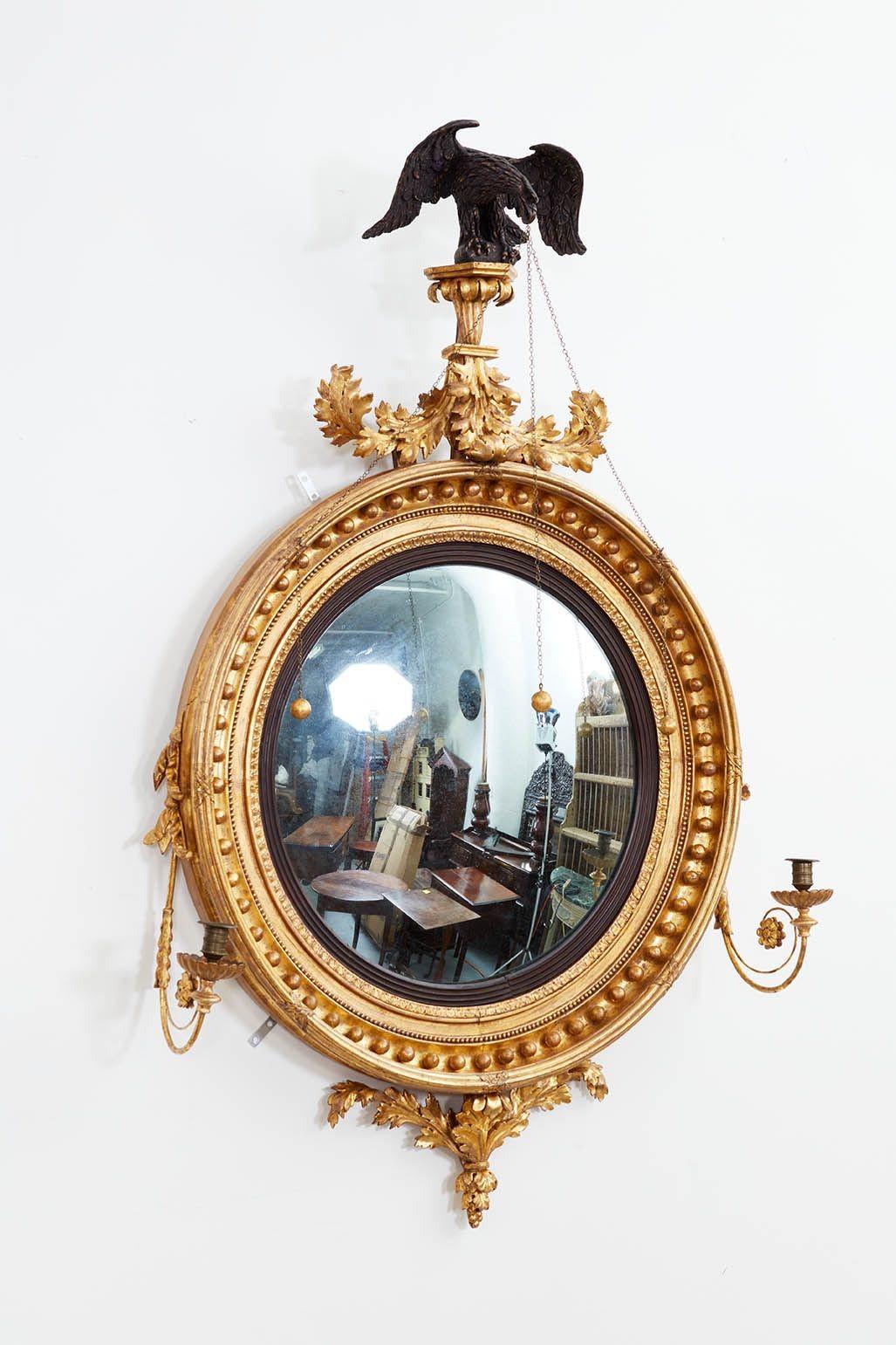 English Regency bullseye mirror of exceptional quality and important scale, circa 1820. Surrounded by spheres and surmounted by a particularly well-executed ebonized eagle, and bordered by brass candle sconce arms. With original mercury glass. The