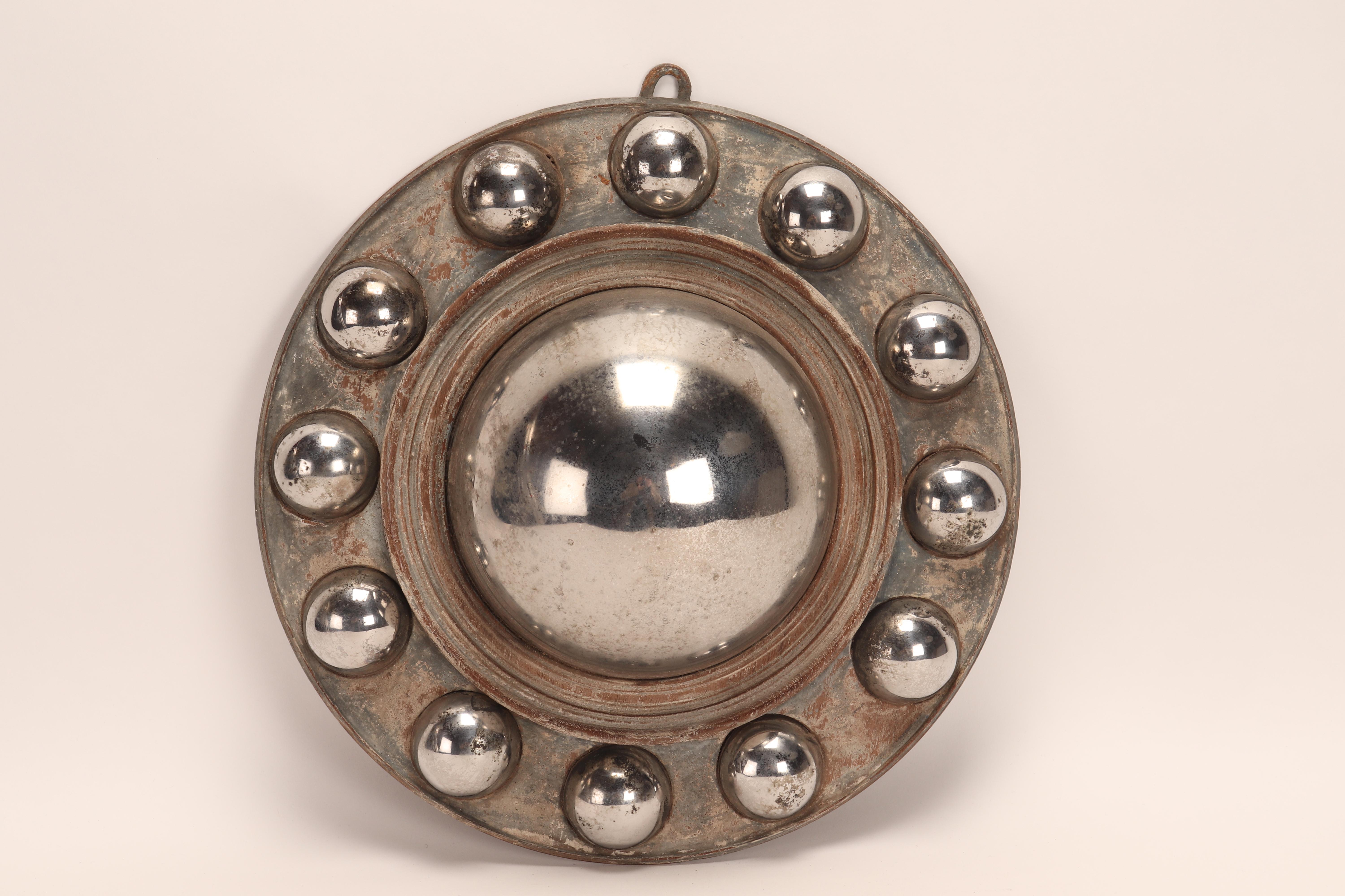 Un grand miroir central convexe en métal, avec 12 petits miroirs convexes en métal le long du bord du cadre rond. Ces miroirs convexes étaient appelés 