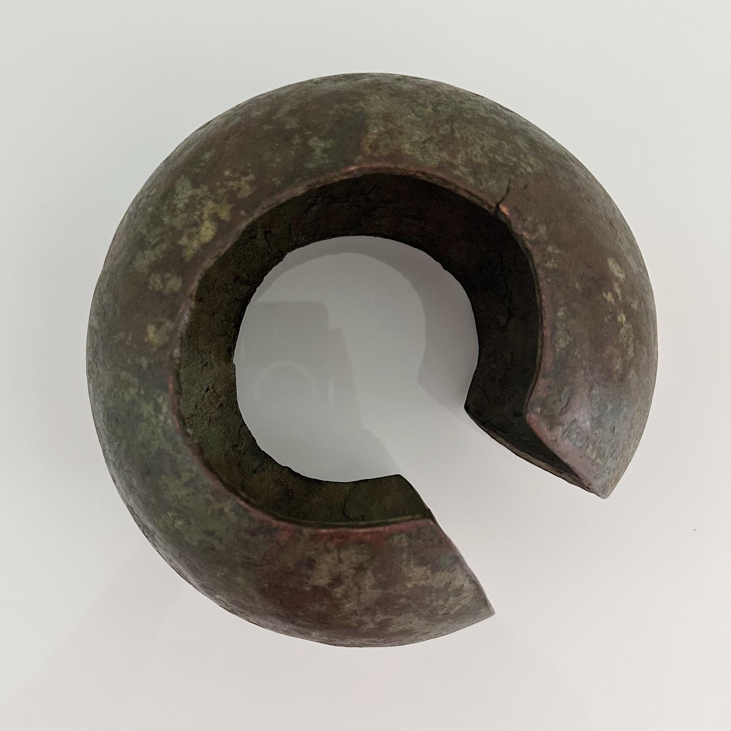 Initially crafted as foot cuffs, these African coins evolved over time, growing in size and weight, ultimately transforming into symbols of wealth and serving as a form of currency. Constructed from patinated copper, they exhibit a distinct