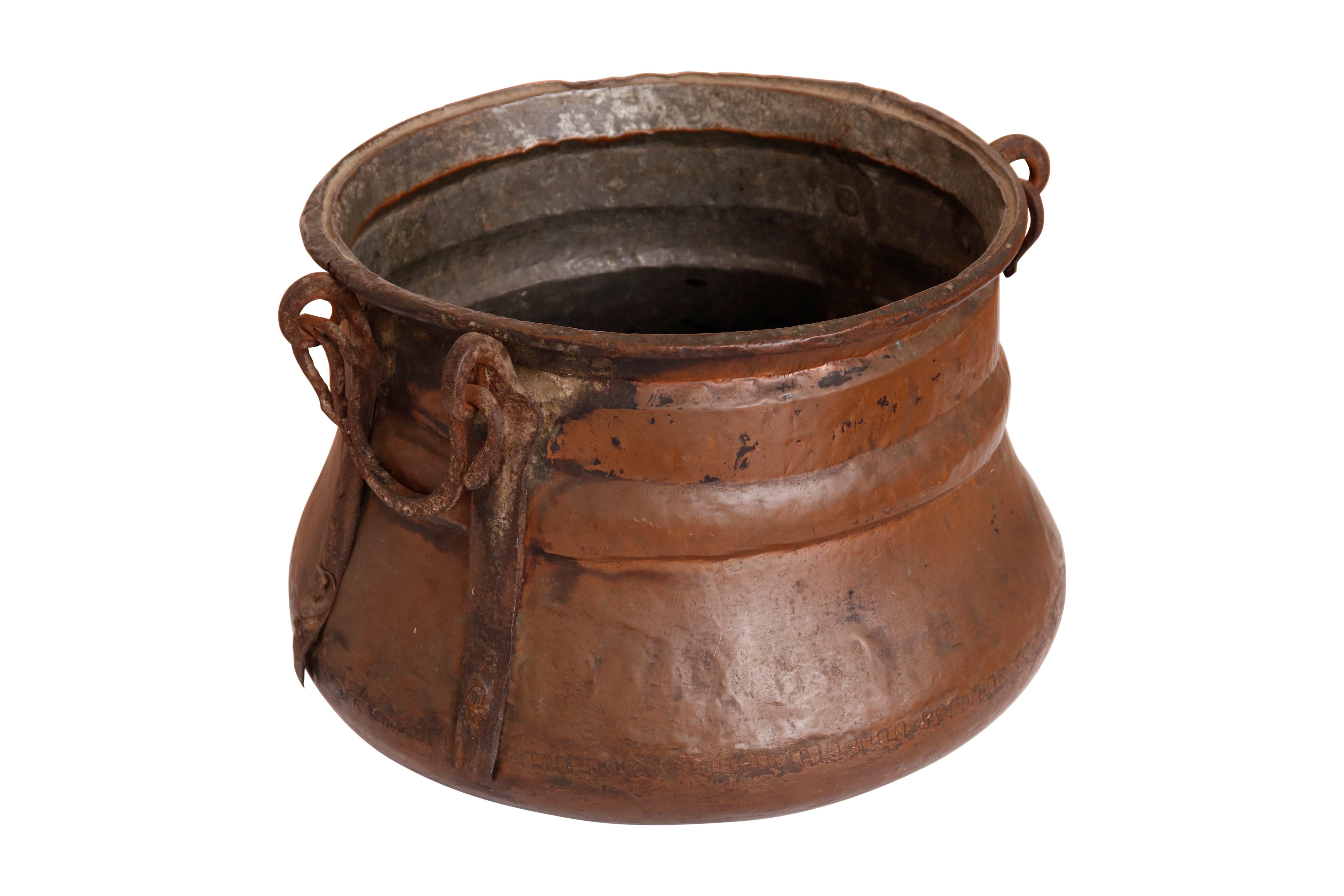 A large, early 20th century hammered copper and tin cauldron with cast iron swan neck handles.
     