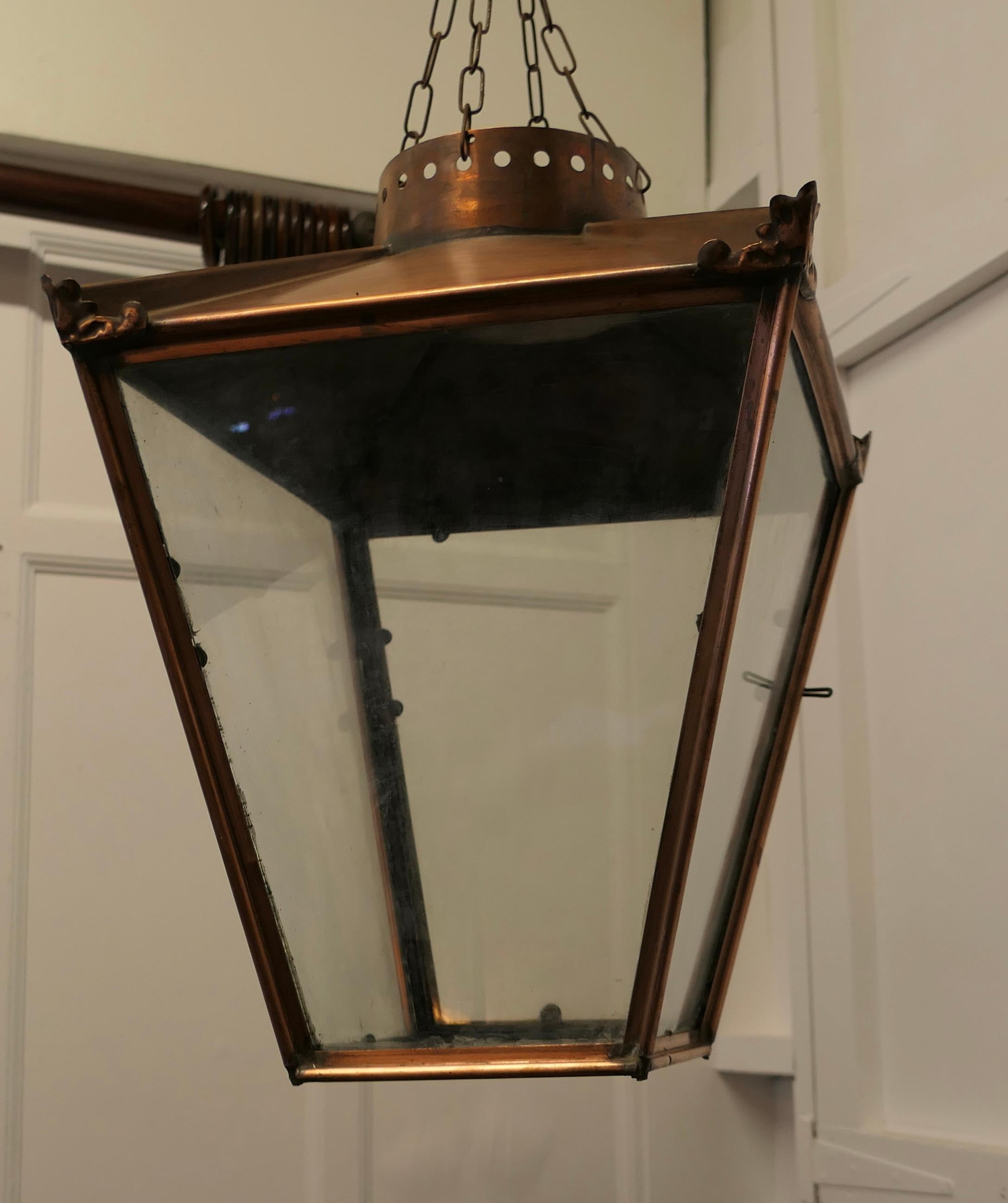 Large Copper Hanging Lantern Lampshade

This is a Lampshade in the form of a Large Copper street light, the Lantern it has a natural oxidised patina, it has glazed sides and at the bottom and it hangs on 4 chains from above
The copper work is old