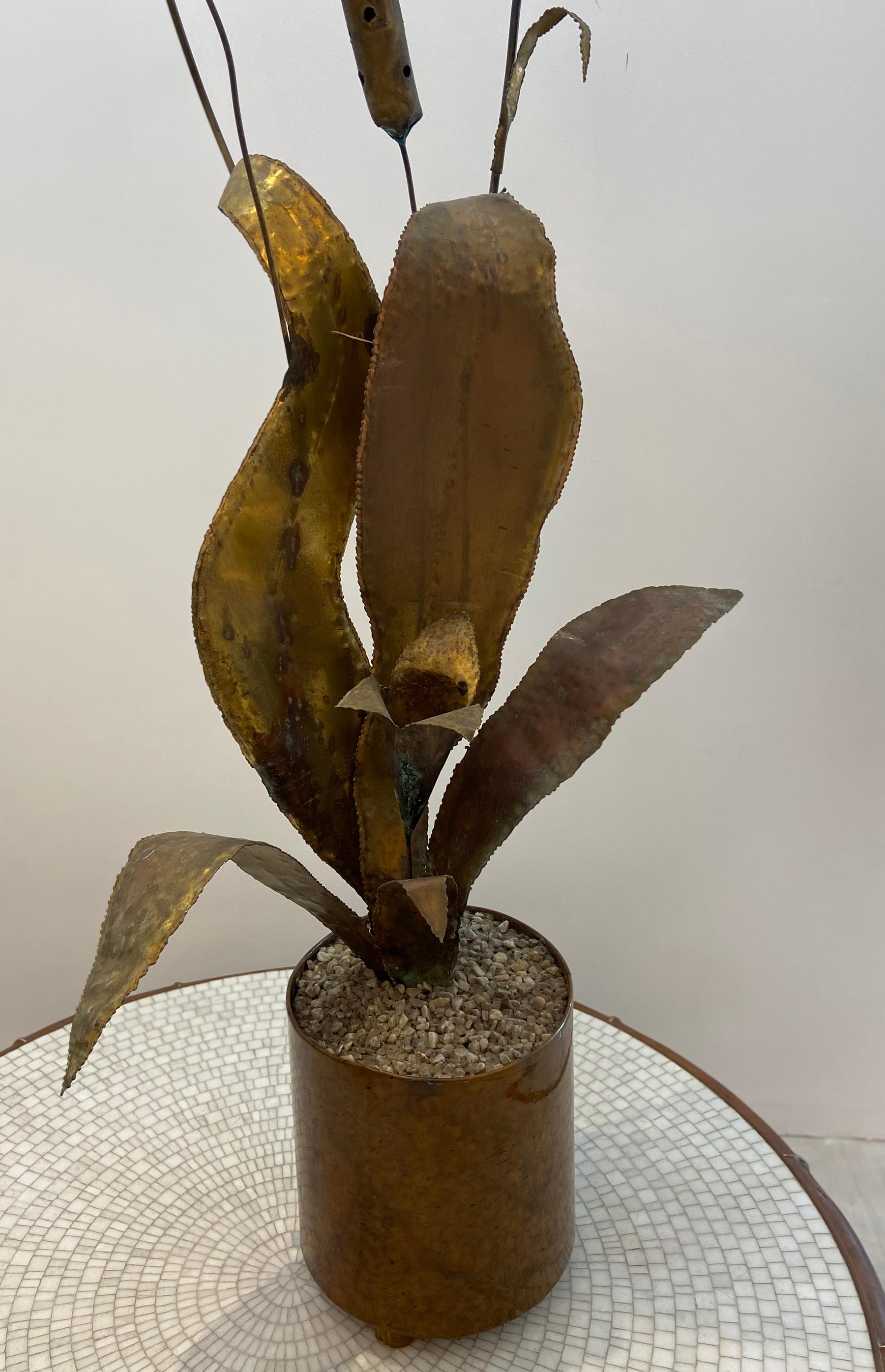 Plant sculpture large leaves with tall cat o nine tails crafted from copper within a copper planter.