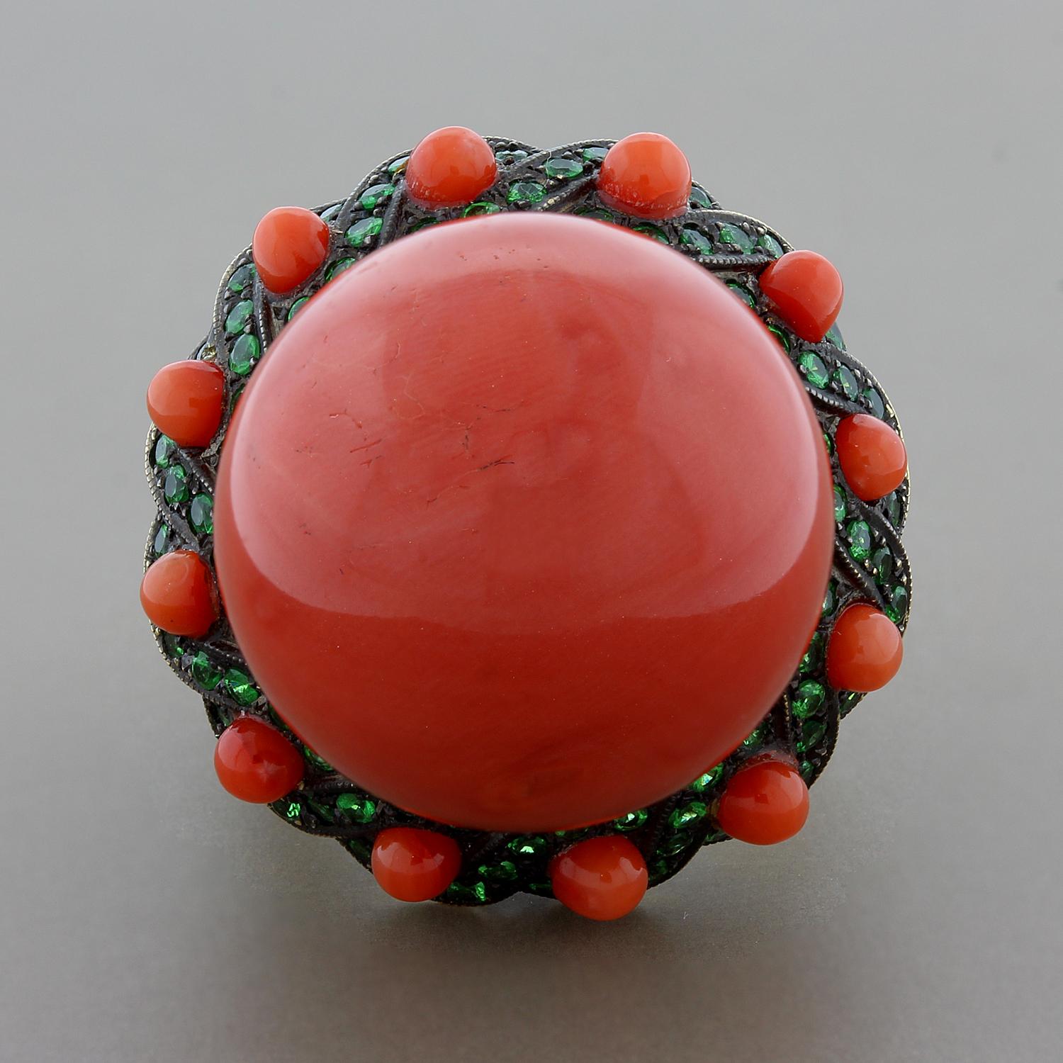 Straight from the reefs! Indulge in this extremely rare 21.3mm piece of coral, perfectly round. The massive coral bead is accented by bright green tsavorite and smaller coral beads, set in 18K yellow gold with a black rhodium finish giving the piece
