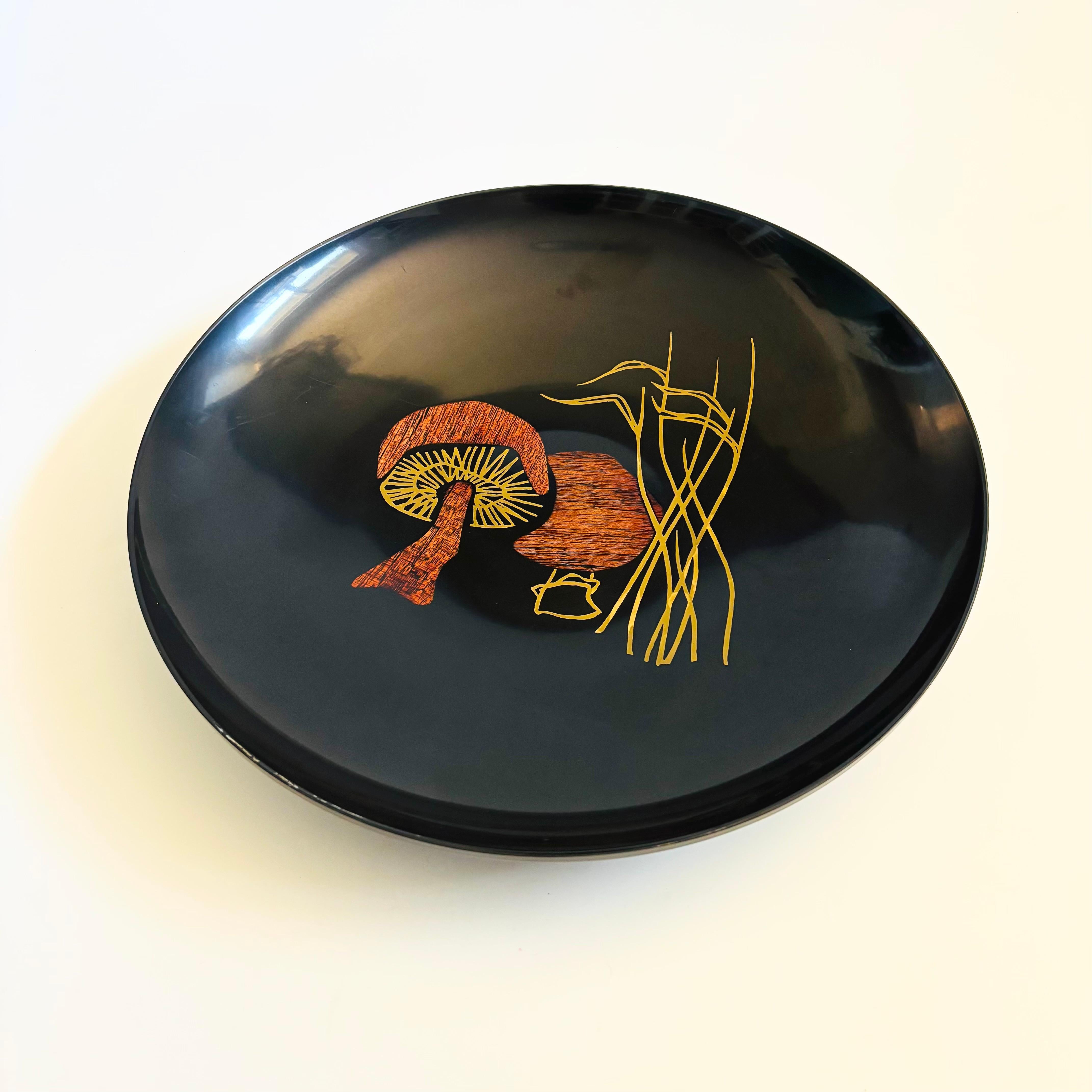 Un grand plateau circulaire vintage de Couroc de Monterey, CA. Fabriqué en phénolique noir satiné, décoré au centre d'un motif de champignon en bois incrusté et en laiton. Autocollant d'origine au dos. Belle taille avec une légère forme de bol.

