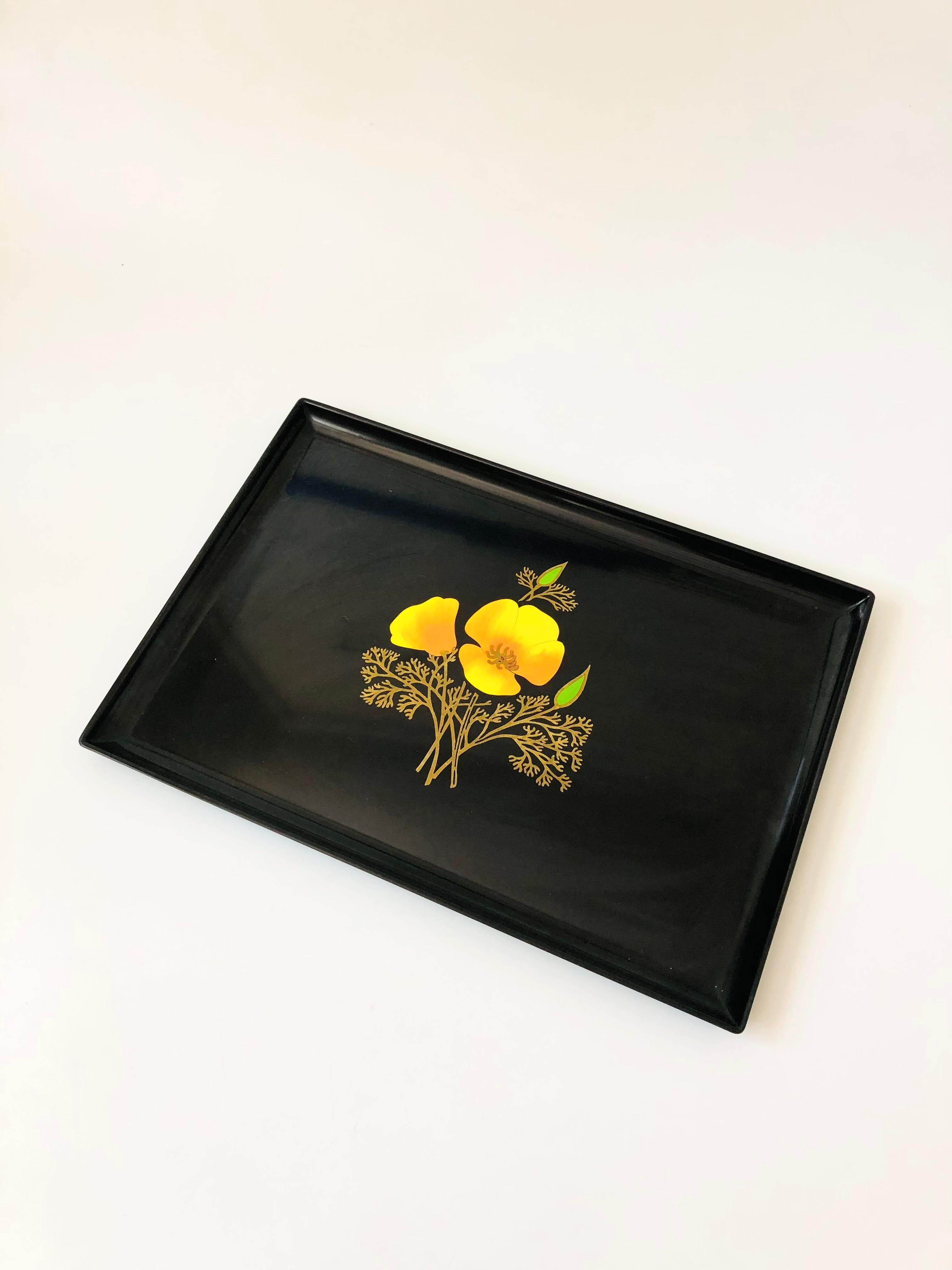 A large vintage rectangular resin tray. Decorated in the center with a California poppy outlined in brass. Made by Couroc, original stickers are on the back.

