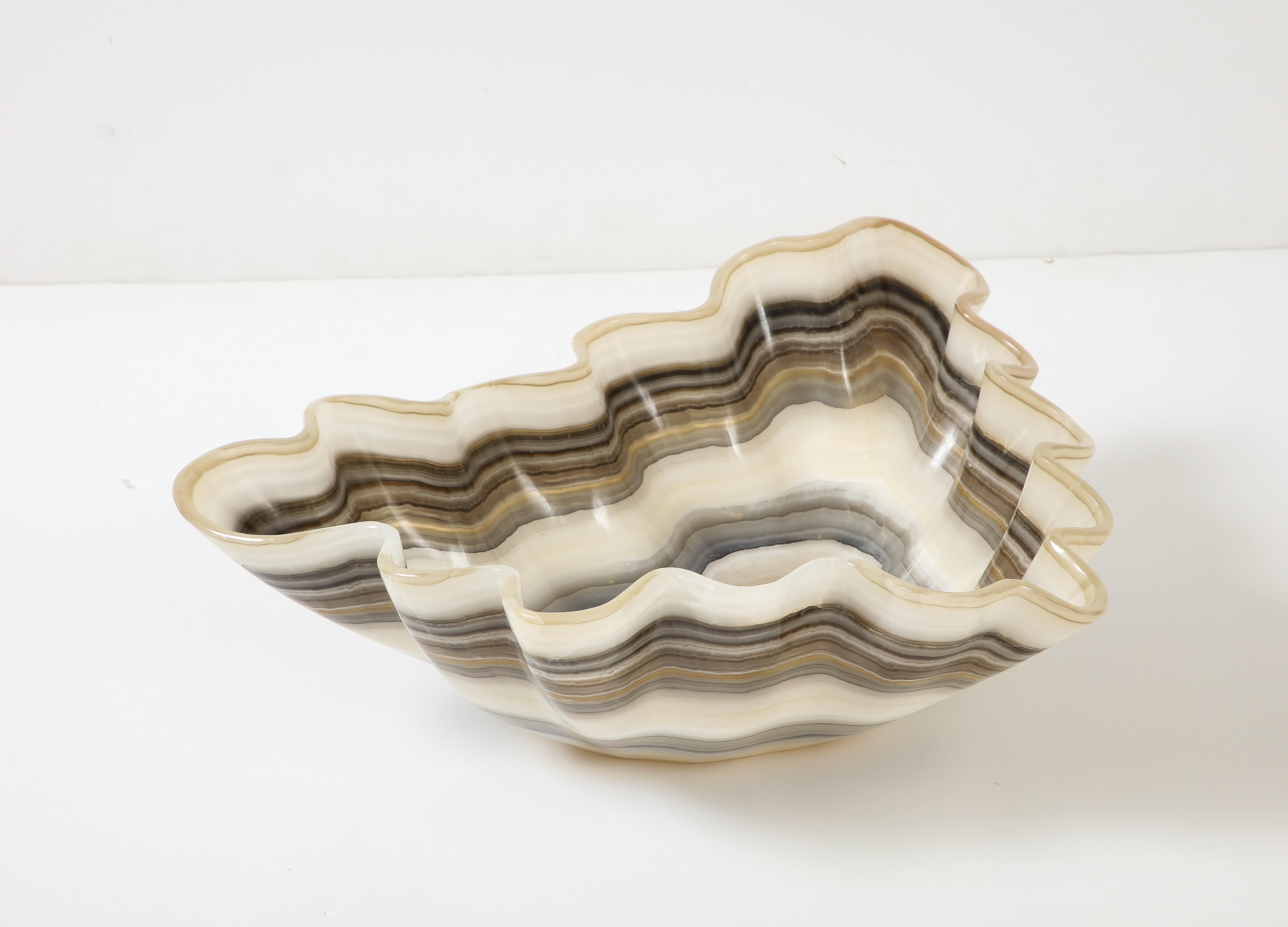 A hand carved polished onyx bowl or centerpiece in an impressive size with a scalloped edge banded with undulating rings of cream, taupe, dark brown, beige, tan, gray and charcoal. Utilitarian and stunning, this centerpiece works with a variety of