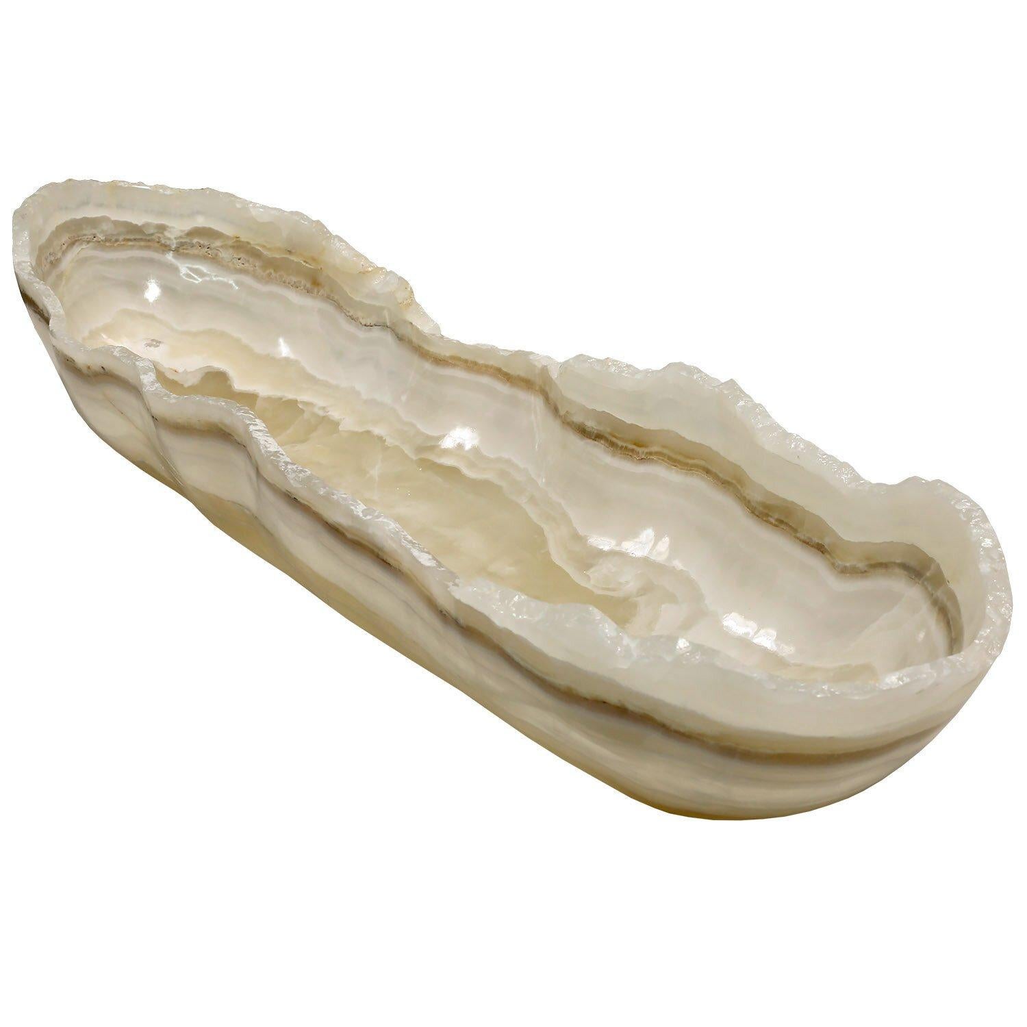 Handmade in Mexico
Carved from a single piece of onyx
One of a kind
35.75 x 10 w x 5.5 h in. / 91 l x 25 w x 14 h cm

A long oval shaped, creamy, stone bowl with a swirled interior pattern created by the natural layering of the onyx. The edges