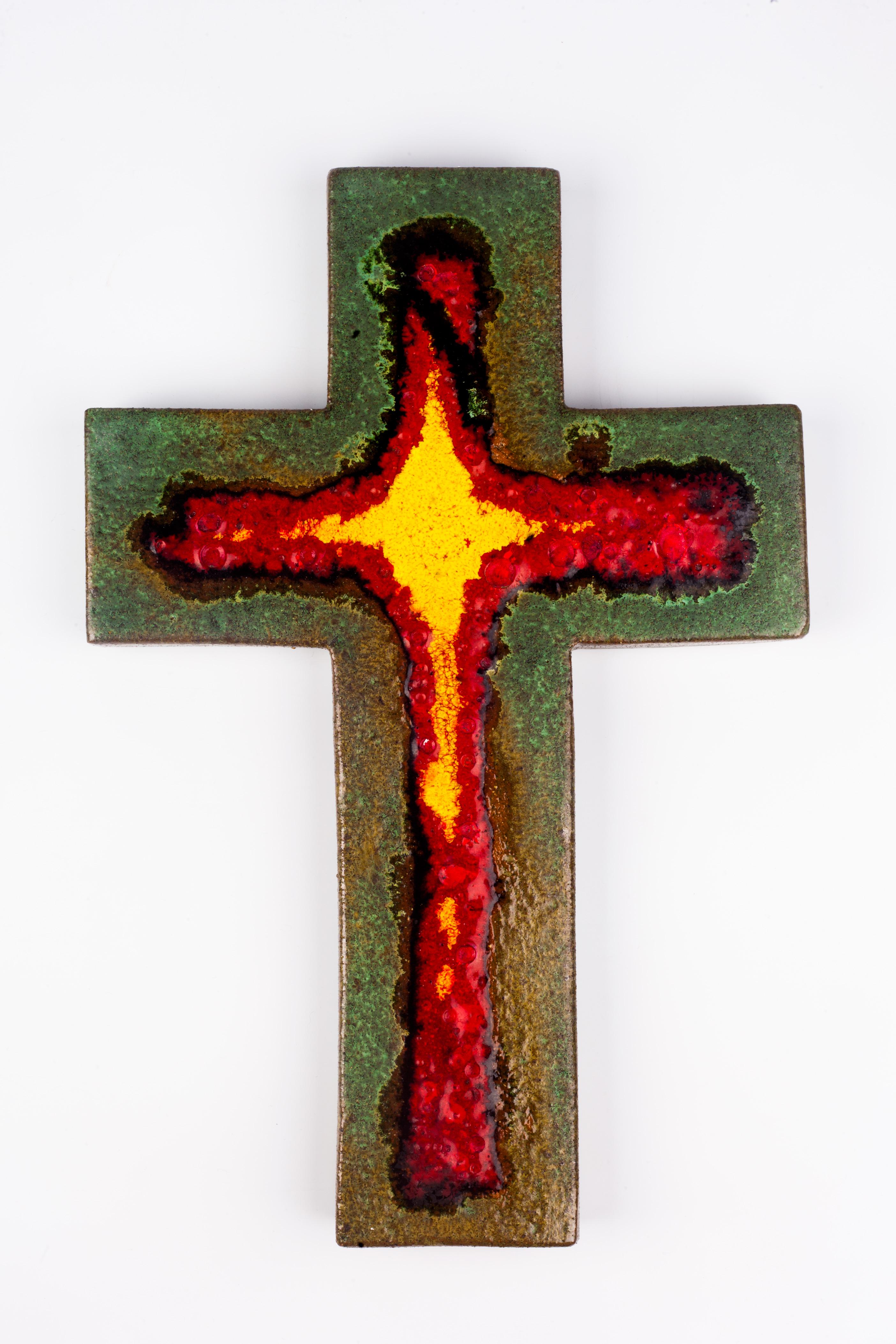 Eleven inch tall wall crucifix in ceramic, handmade in Belgium in the 1980s. Glossy marine green cross with red and yellow interior cross shape. The color red has fat lava textured craters. A large piece with eye catching juxtaposition of colors.