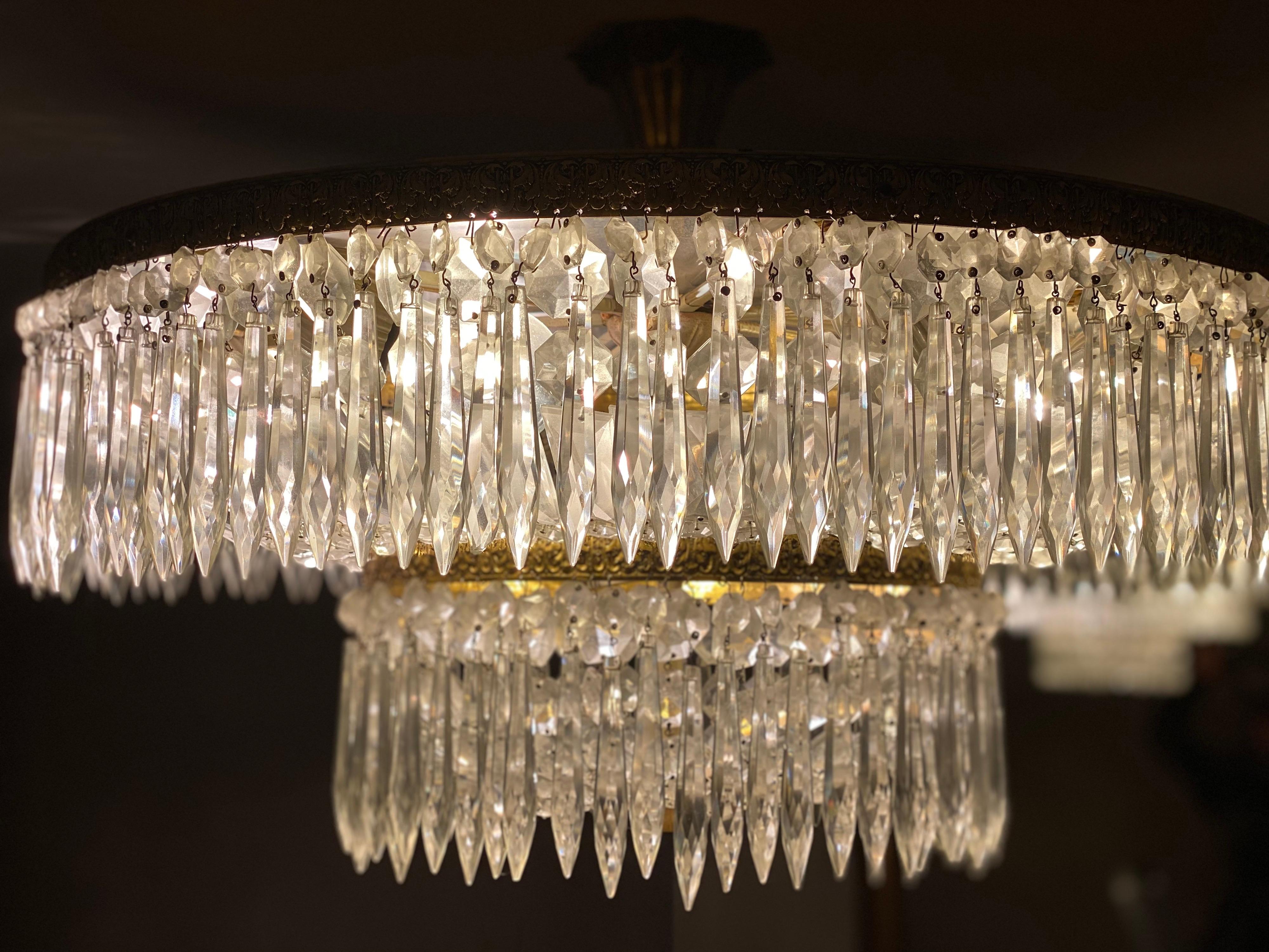 This glamorous Hollywood-Regency style chandelier flush mount was mad in the 1970s with a gilt brass structure. Item of excellent workmanship. The chandelier features hundreds of faceted crystals which create a charming light diffusion.The