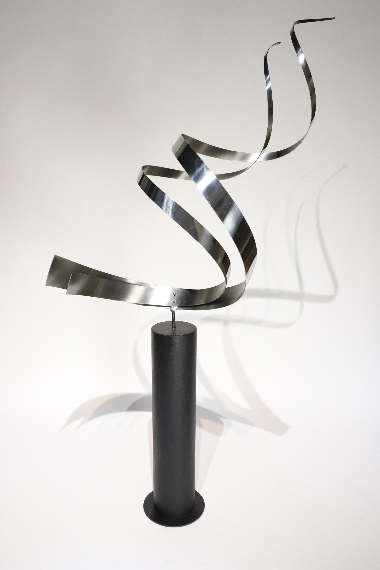 Stunning stainless steel “swirl” floor sculpture by Curtis Jere. Swirl sits atop a painted black steel base and swivels, allowing the perfect placement. Pictured with Milo Baughman for Thayer Coggin dining chairs for scale. This is a large piece and
