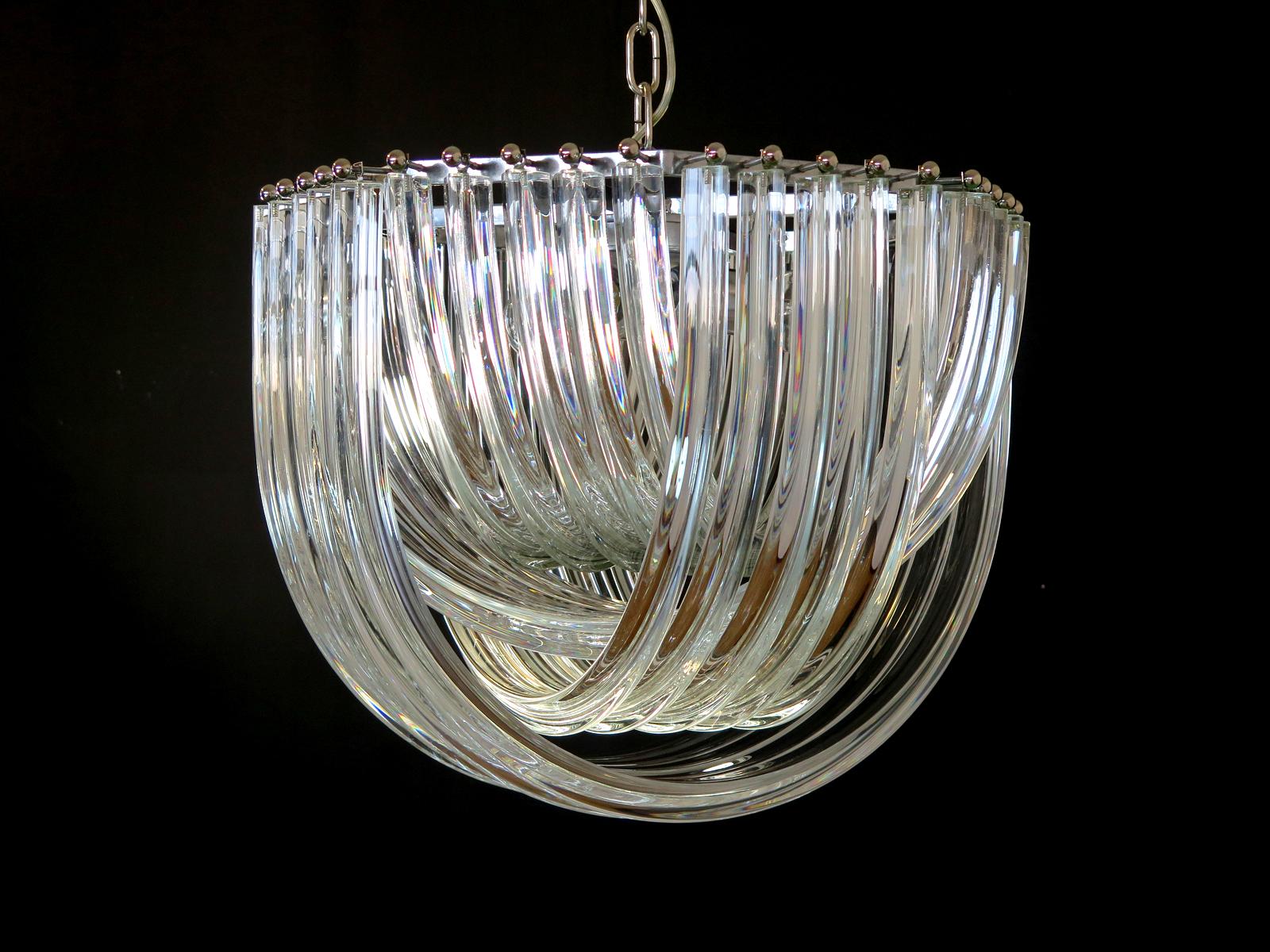 Murano light transparent glass chandelier with four layers of curving “triedri” glass prisms on an octagonal chrome structure. A dynamic form, changing as you move around it, due to the overlapping levels of transparent
glass with light shining
