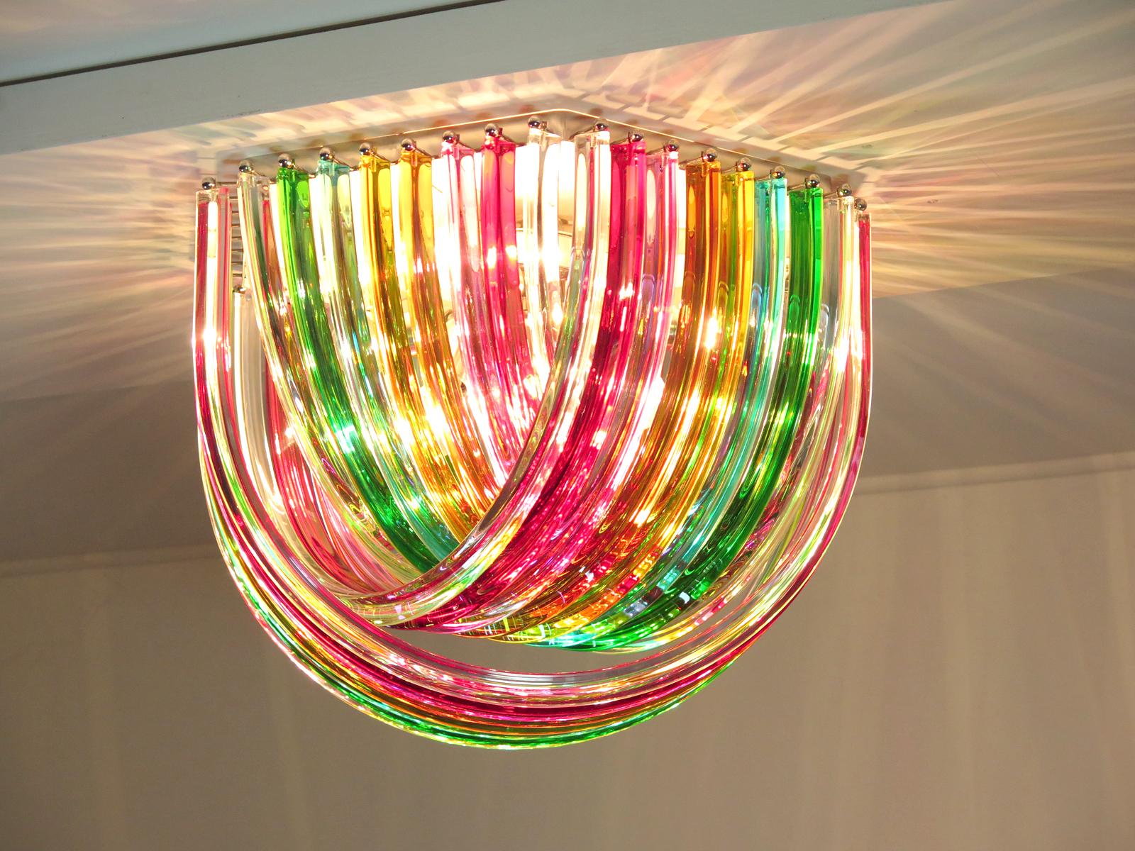 Murano ceiling light multicolored glass with three layers of curving “triedri” glass prisms on an hexagonal chrome structure. A dynamic form, changing as you move around it, due to the overlapping levels of multicolor glass with light shining