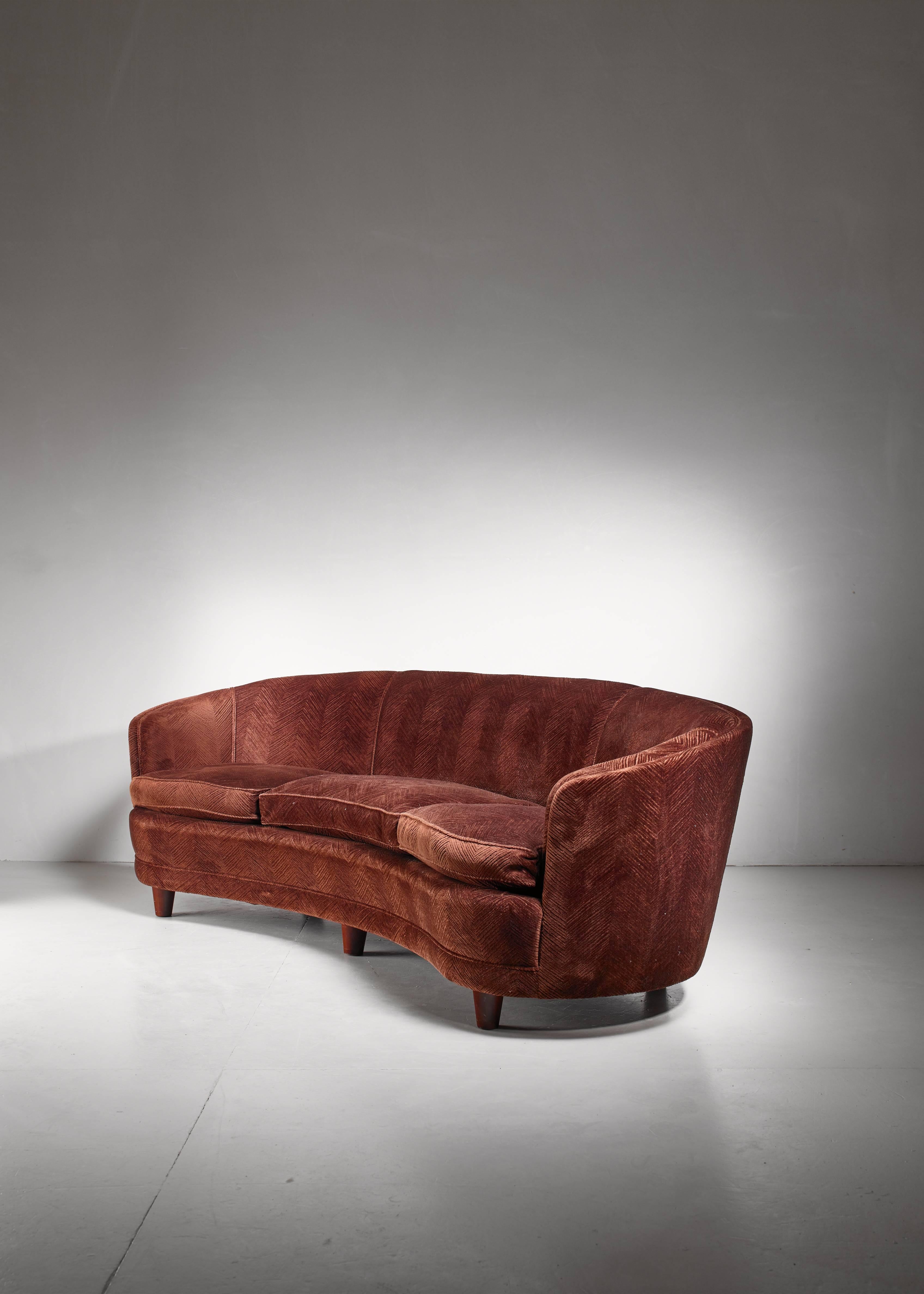 A large (244 cm long) brown, curved sofa from Scandinavia, in the manner of Greta Magnusson-Grossman. The sofa has the original dark brown textured fabric upholstery and has three dove filled loose cushions.
A very inviting and comfort offering