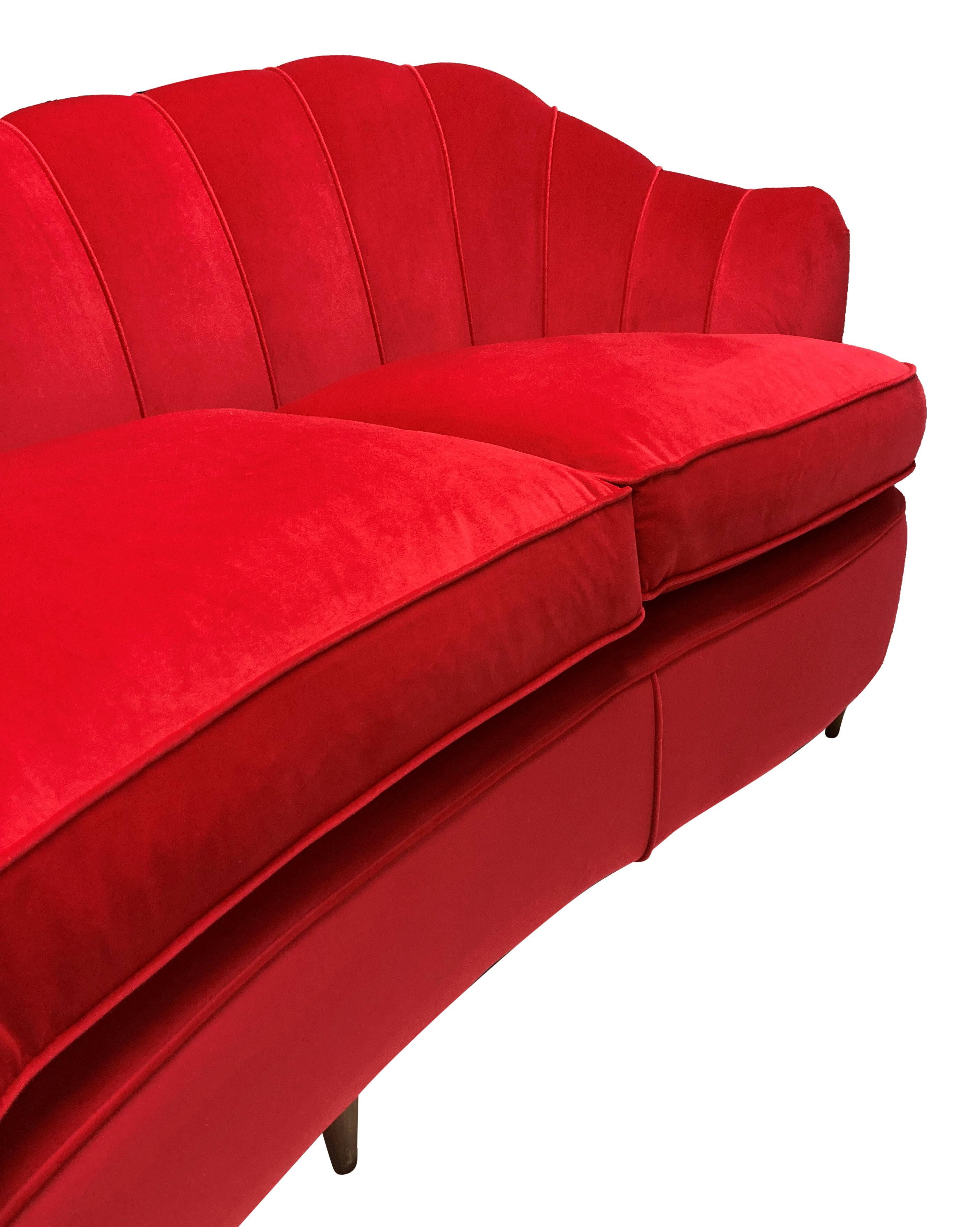 A large, curved sofa with scalloped back in the style of Gio Ponti. Of generous proportions, with three newly feathered cushion seats and newly upholstered throughout in red velvet.