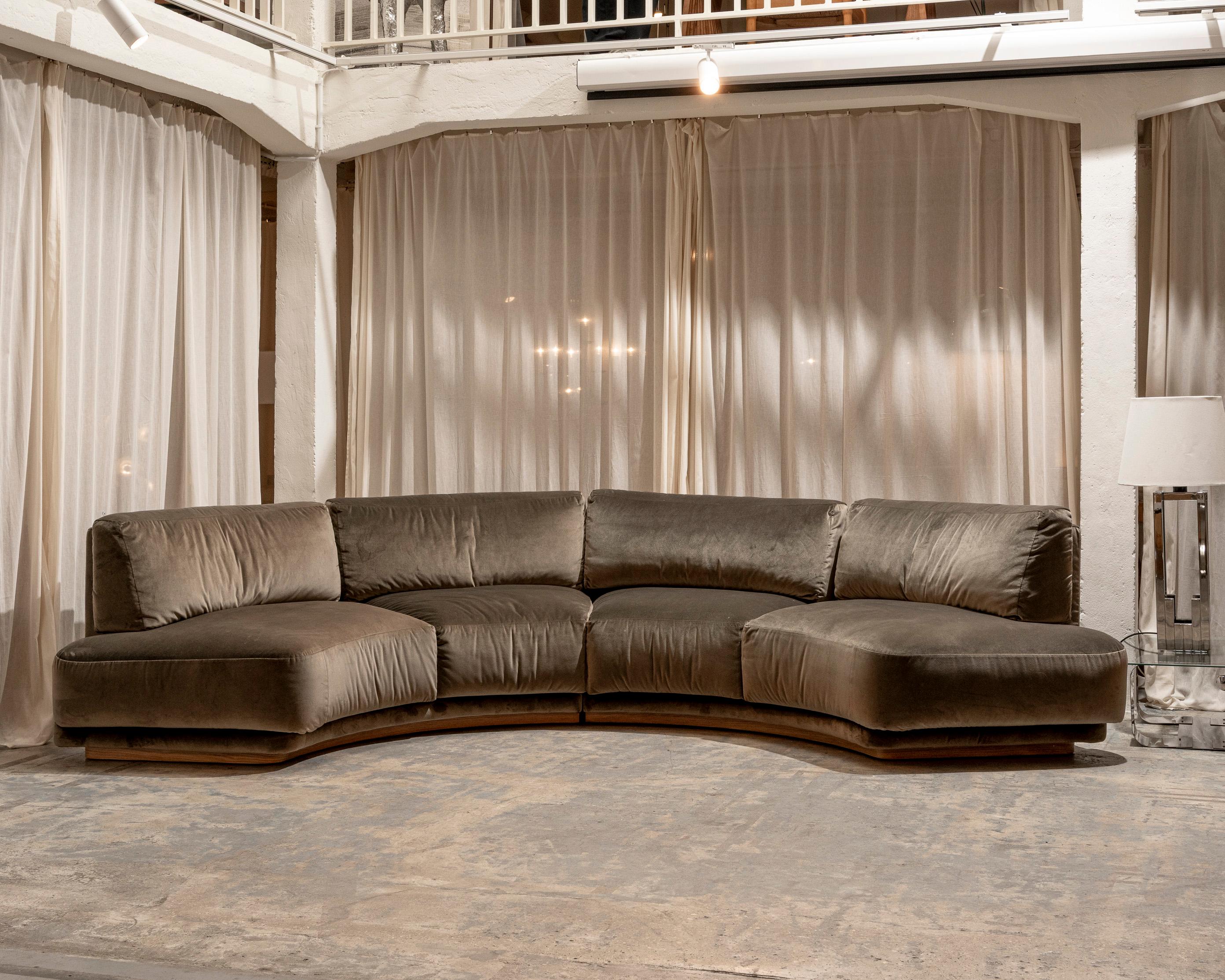 Grande divano curvo composto da due moduli, rivestito in un elegante velluto color tortora di Pierre Frey. Base in legno pregiato, in ottime condizioni. Gli elementi dello schienale e della seduta sono rimovibili e vengono tenuti in posizione da