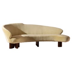 Large curved sofa with carved wooden supports, Italy, 1950s