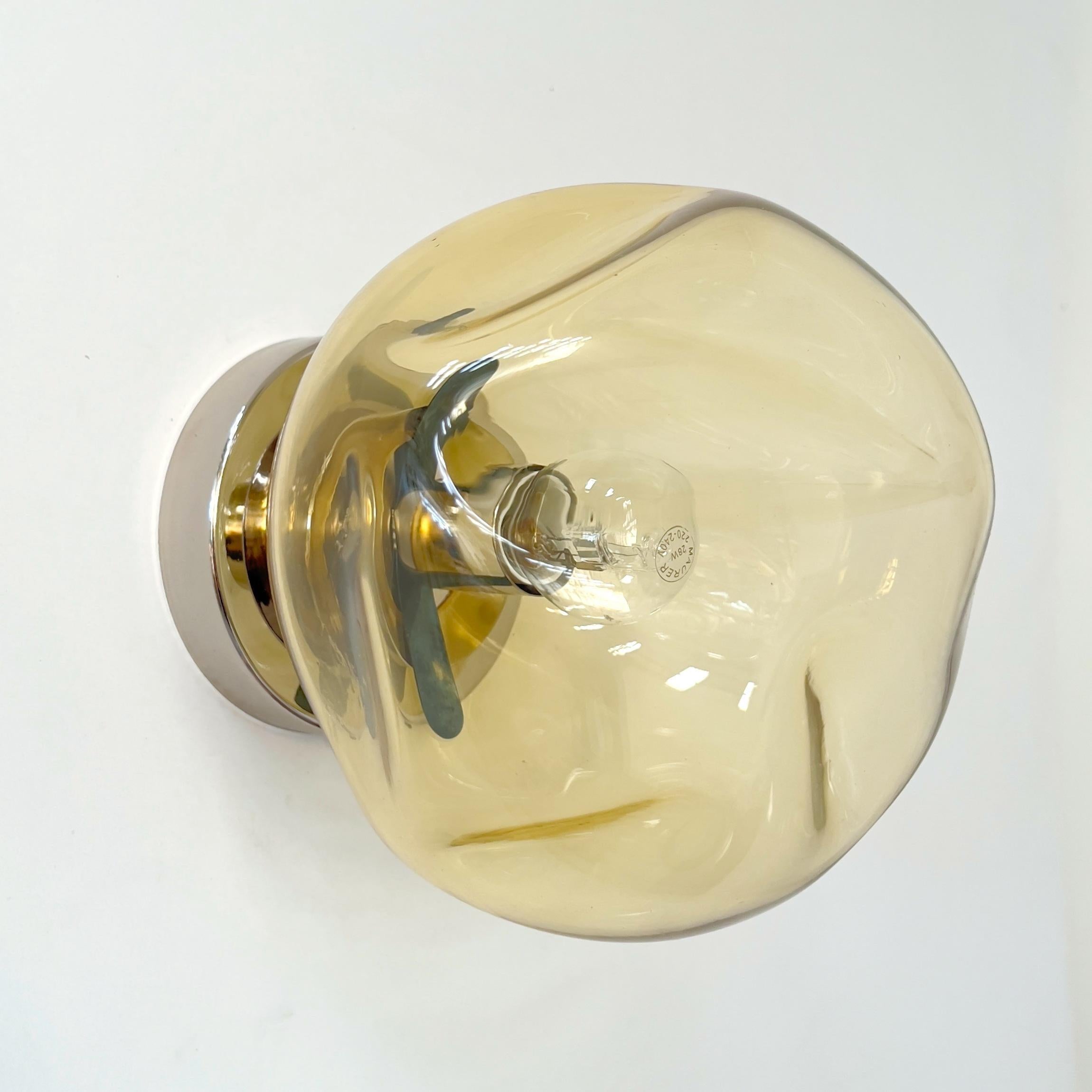 Aplique de pared o empotrable moderno italiano con una gran pantalla de cristal de Murano alabeado de color ámbar montada sobre una estructura de metal acabado en níquel pulido, diseñado por Fabio Bergomi para Fabio Ltd, fabricado en Italia.
1 luz /