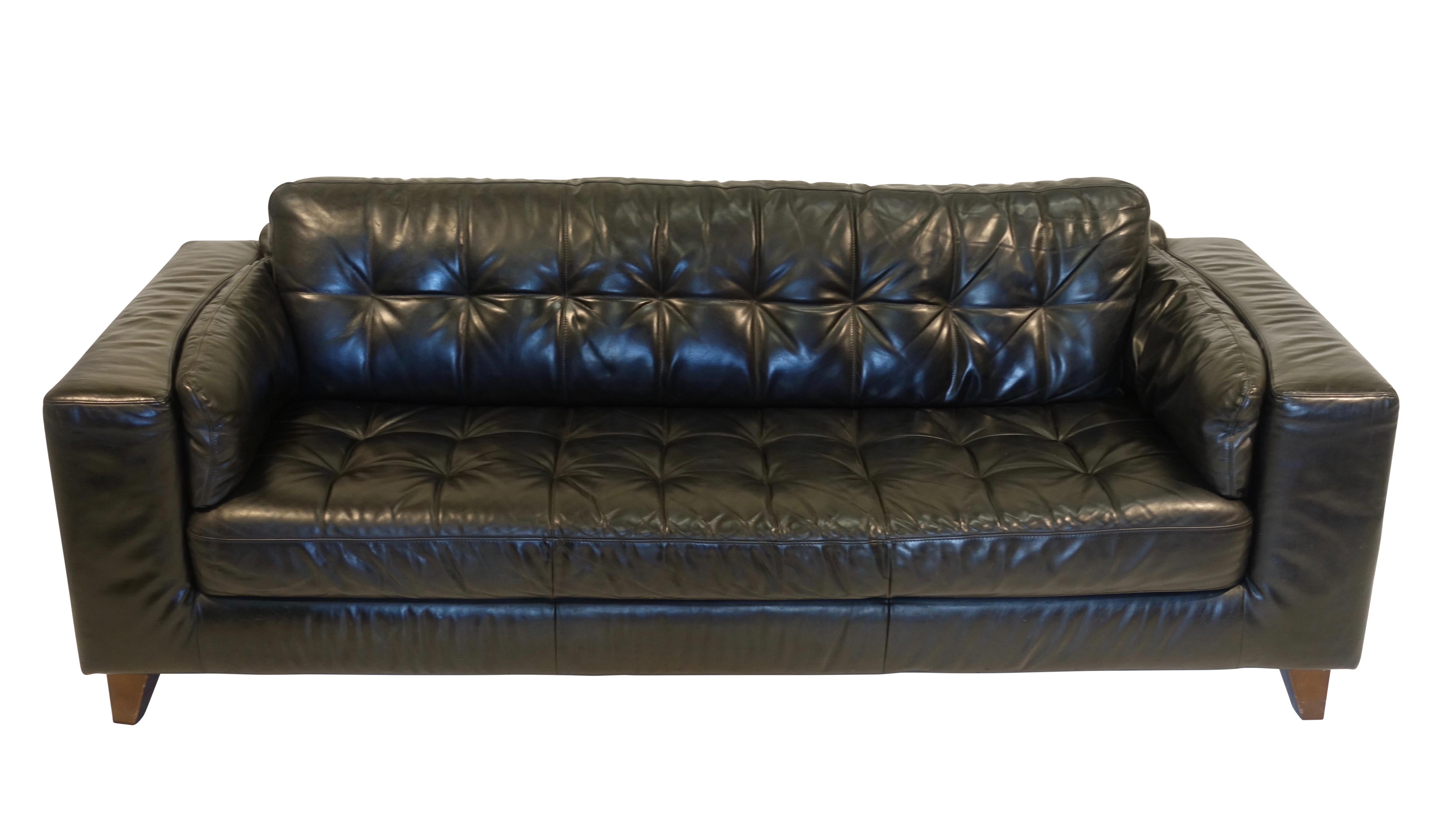 An unusually large vintage Italian black leather sofa with tufted seat and back cushion, having broad arms and standing on tapering wooden legs, circa 1970s.