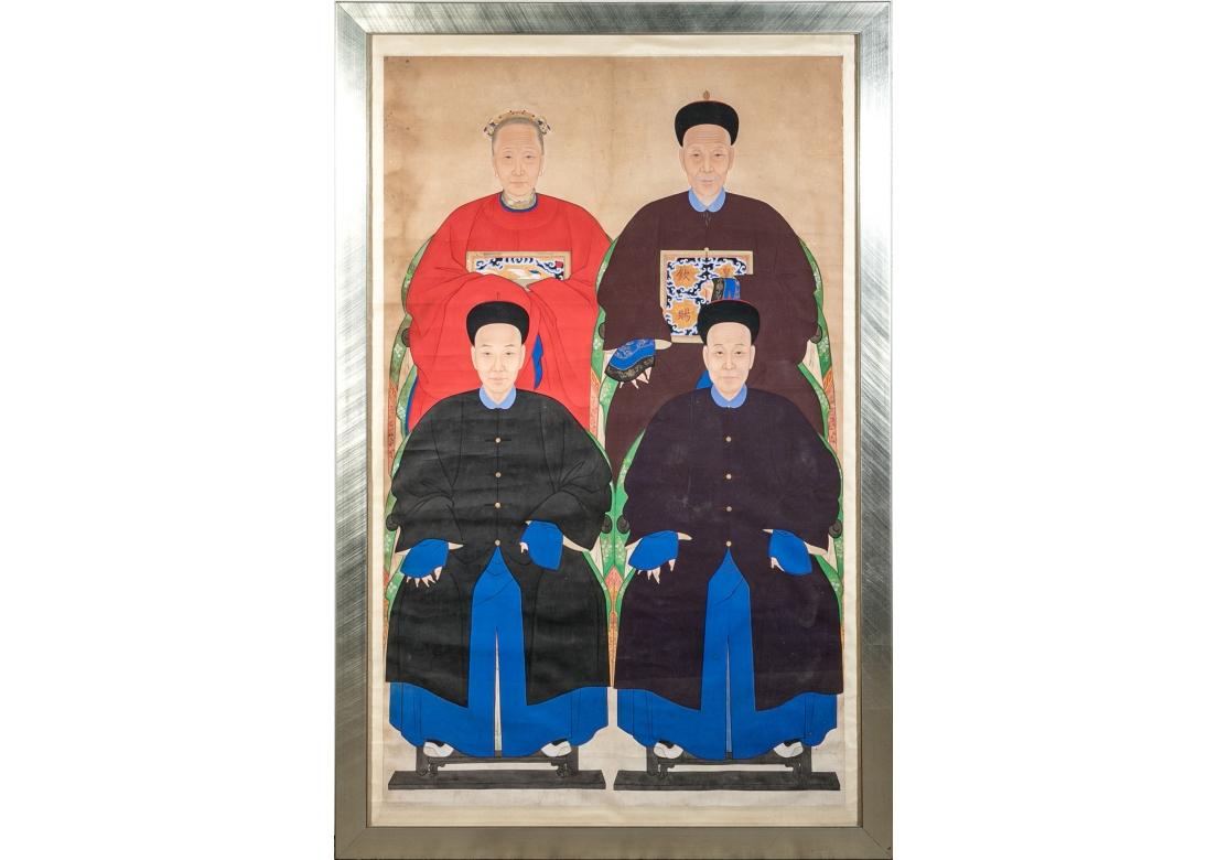 Large custom framed hand painted Chinese ancestral portrait with one female and 3 male figures attired in traditional dress. The upper figures with pictorial appliqués to the front of the garments while the seated figures are attired in plain robes.