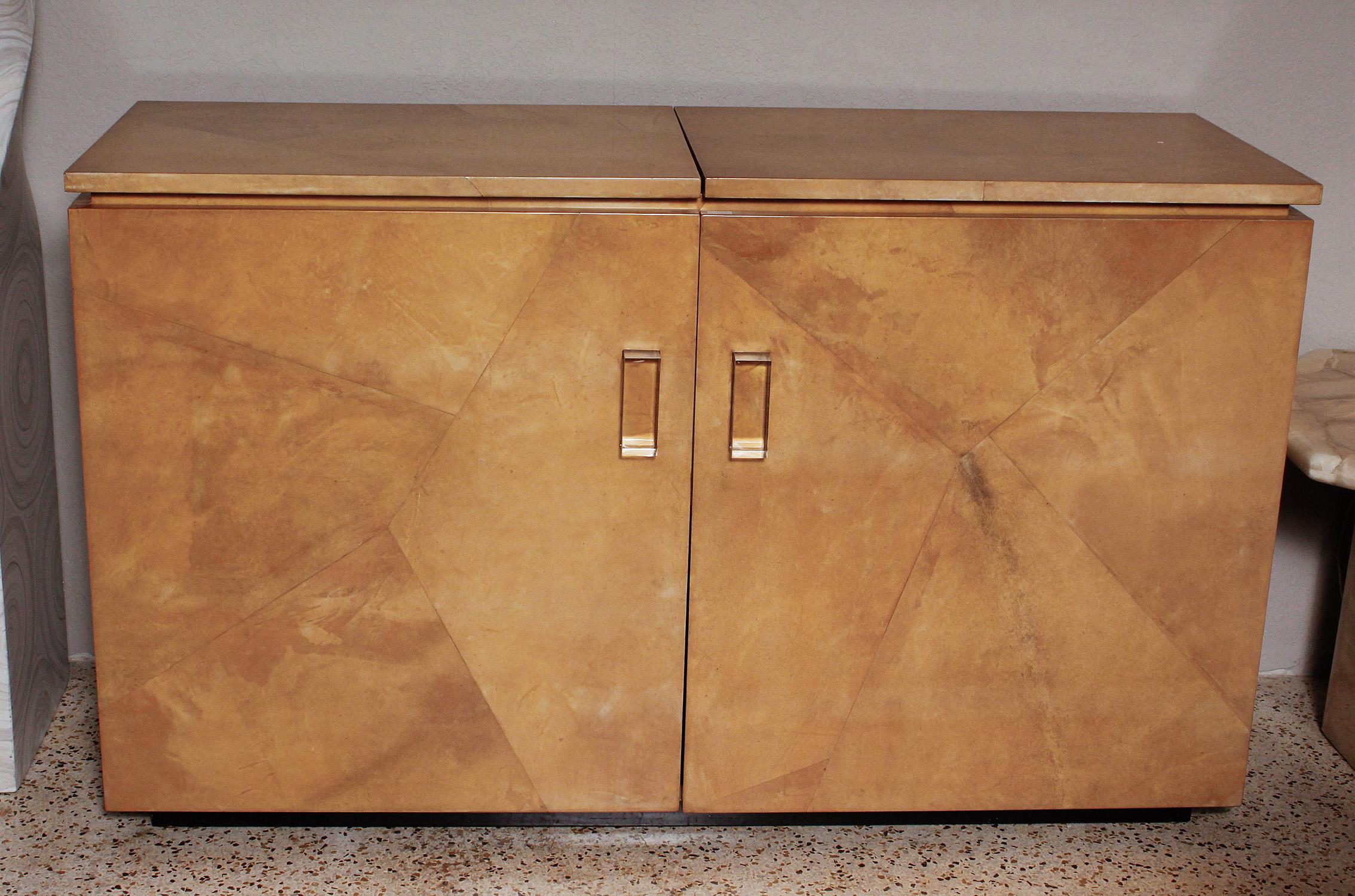 This 1970s custom-made bar cabinet in geometrically pieced goatskin with chunky acrylic block handles features hinged-top access, with two drawers and multiple glass shelves below. Designer unknown.