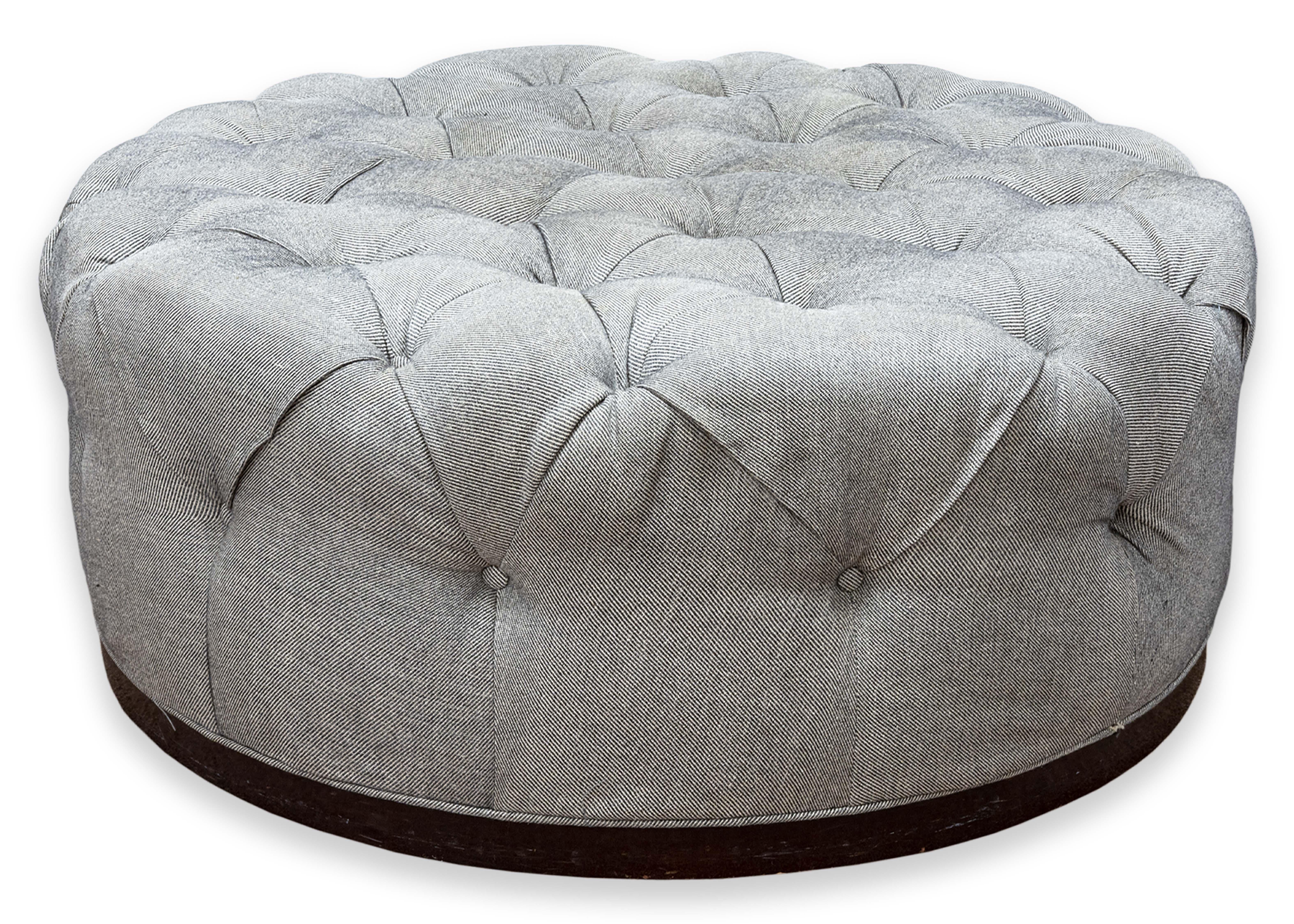 A large custom made tufted ottoman. This lovely living room piece is custom made and in great condition. This piece features an oversized, tufted design. The fabric is a beautiful subdued gray color with deep tufts. The whole unit sits on an