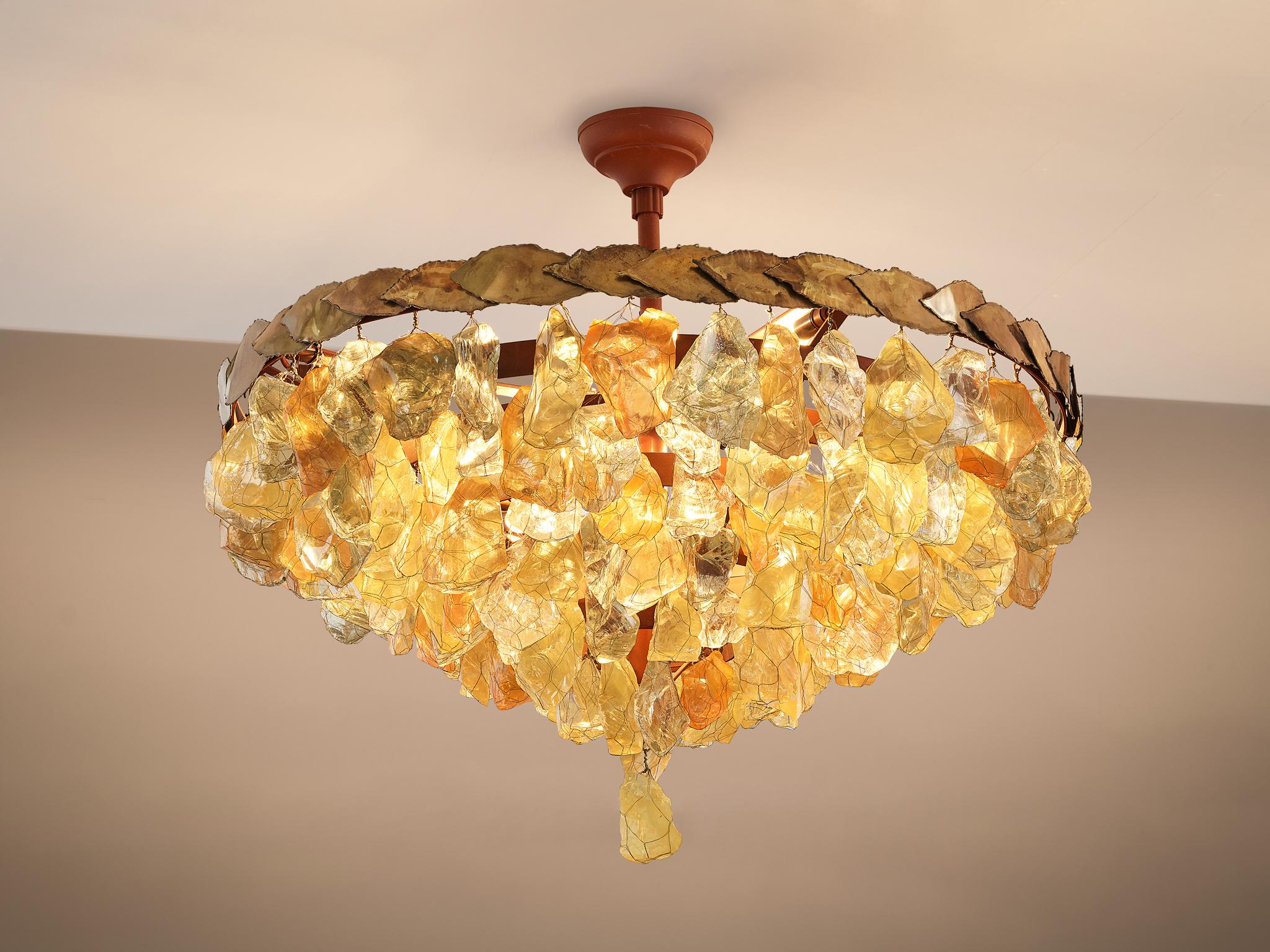 Chandelier, glass, brass, metal, France, 1950s.

This pendant features a diversity of different forms of and colors of rough glass chunks. The chunks feature autumnal colors. The variety of organic, asymmetrical glass elements is held together with