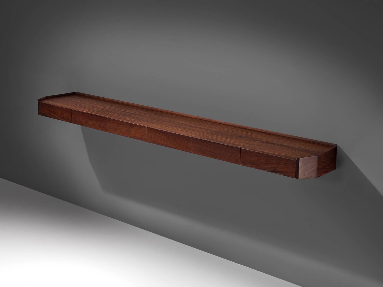 Wall shelf, rosewood, Italy, 1960s.

This rosewood piece holds six separate drawers. The piece is spectacular in the sense that it is very long and uniquely shaped. The corners are 'cut off' so to speak, by which a sculptural piece is created that