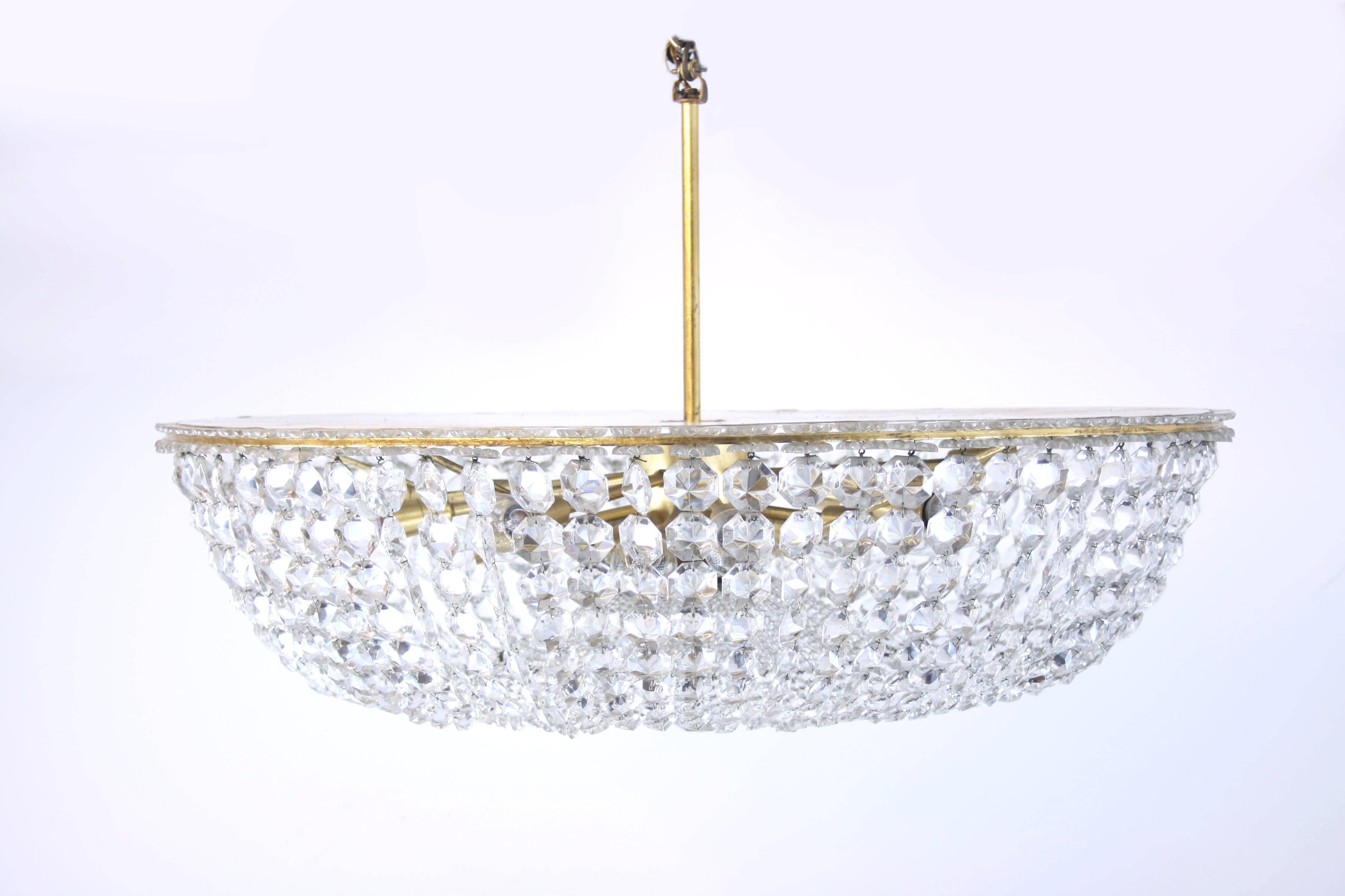 Large and heavy brass chandelier in the style of Lobmeyr, Vienna, on solid cast frame. This impressive pendant is equipped with 20 bulbs and provides a distinguished and noble atmosphere. Its central piece is an edge cutted crystal sphere with a