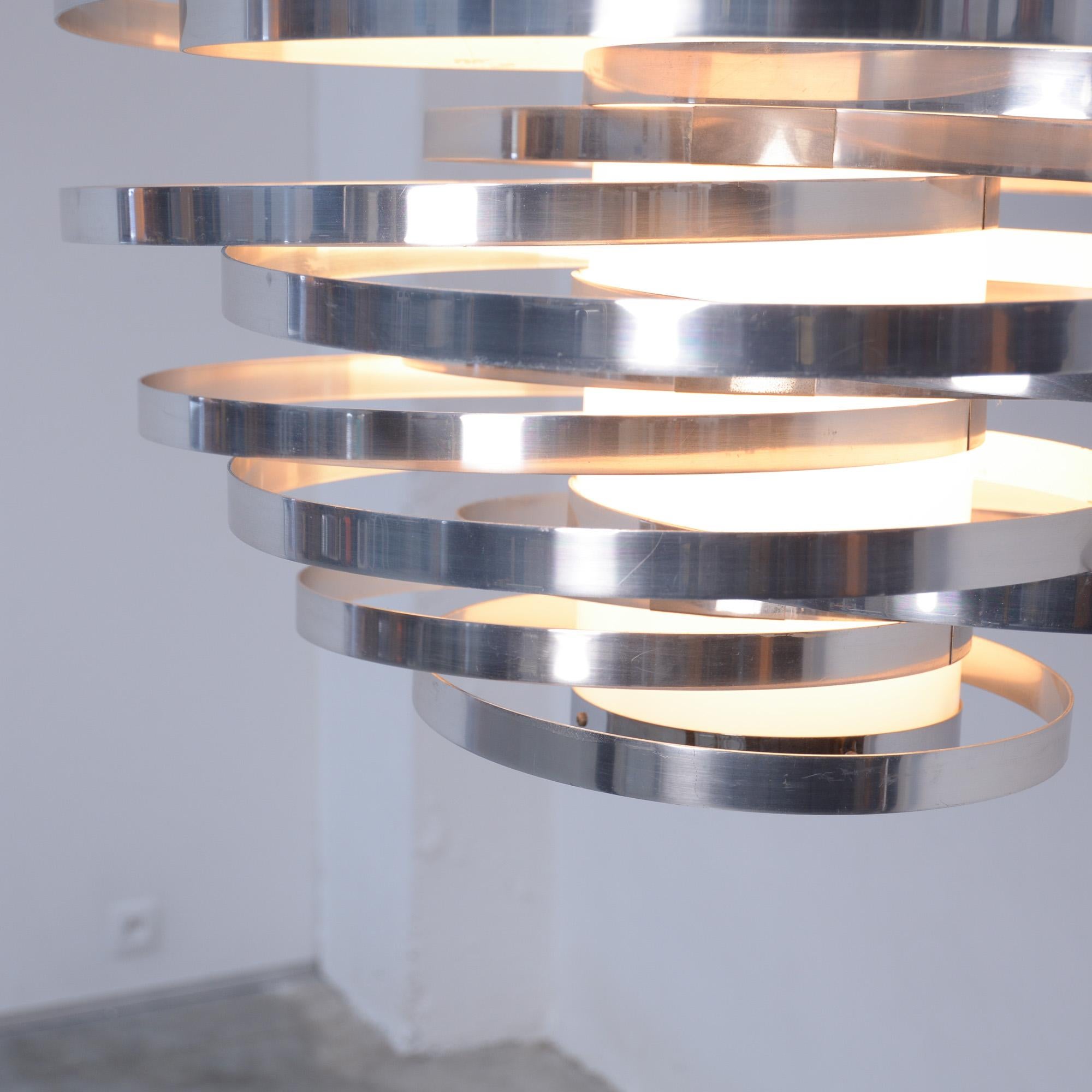 This magical cyclone chandelier was designed by Gaetano Sciolari in Italy in the late 1960s.
This dynamic design is made of a white Plexiglas central cylinder surrounded by aluminium rings.
This chandelier is in very good condition, with normal