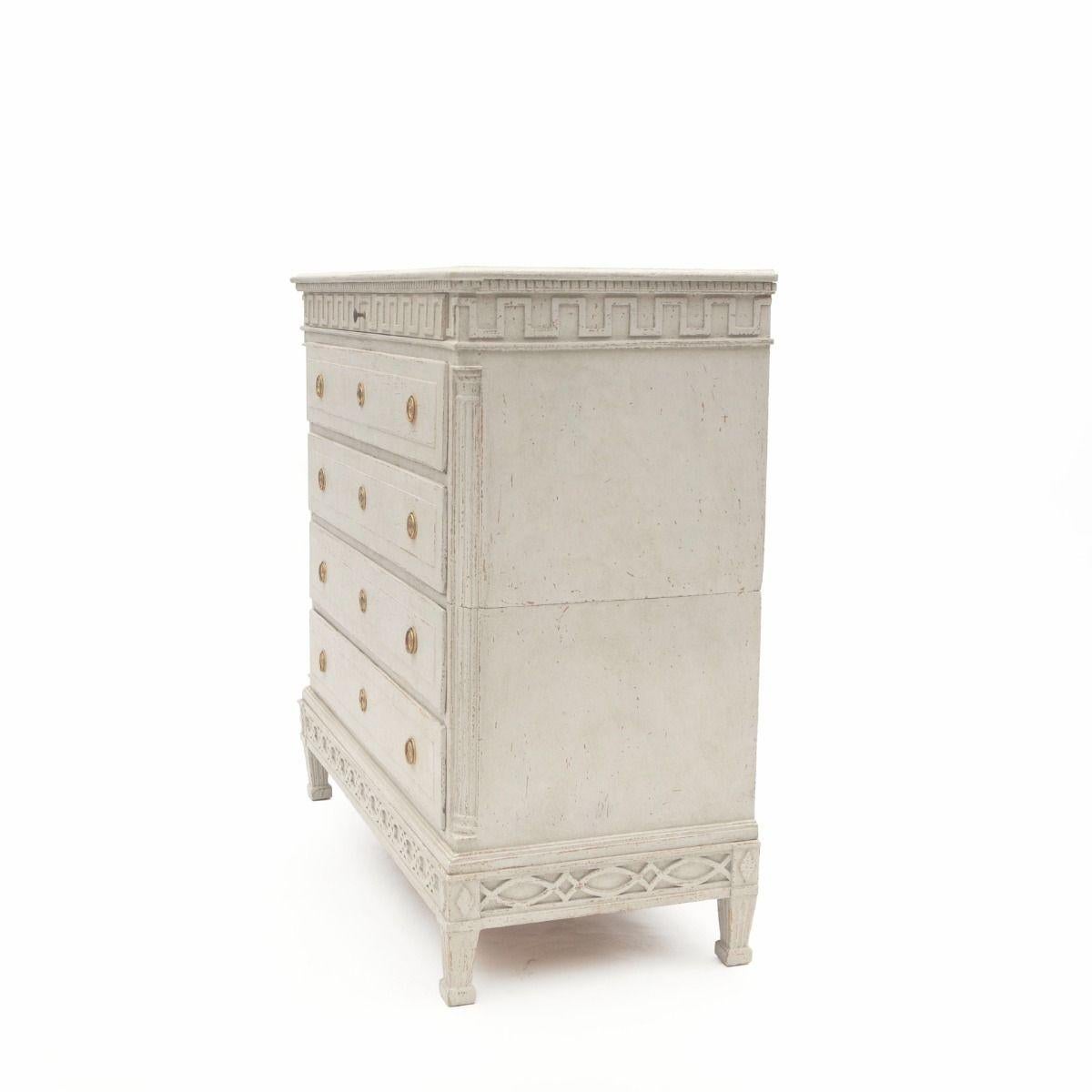 Una grande cassettiera danese Luigi XVI di colore grigio chiaro, in tre parti.
Il bordo della galleria è caratterizzato da un profilo superiore che sovrasta le modanature a dentello intagliate nel legno.
La cassettiera ha 5 cassetti: un cassetto più