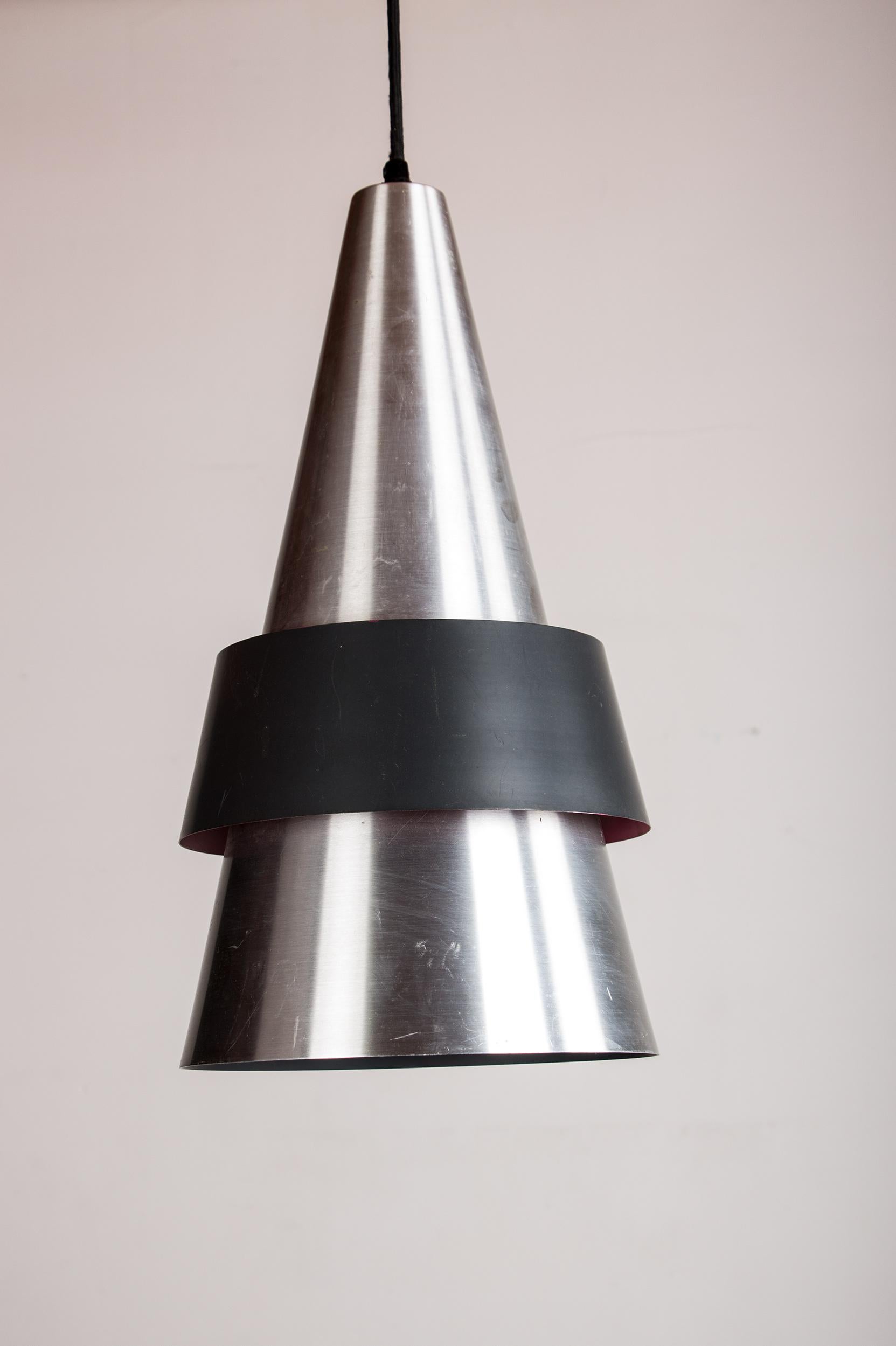 Superbe suspension scandinave. Composé d'un grand cône en aluminium doublé d'un cône en métal noir grainé, il offre un éclairage nuancé très intime. Hauteur totale largement réglable selon les besoins (plus de 150 cm).
