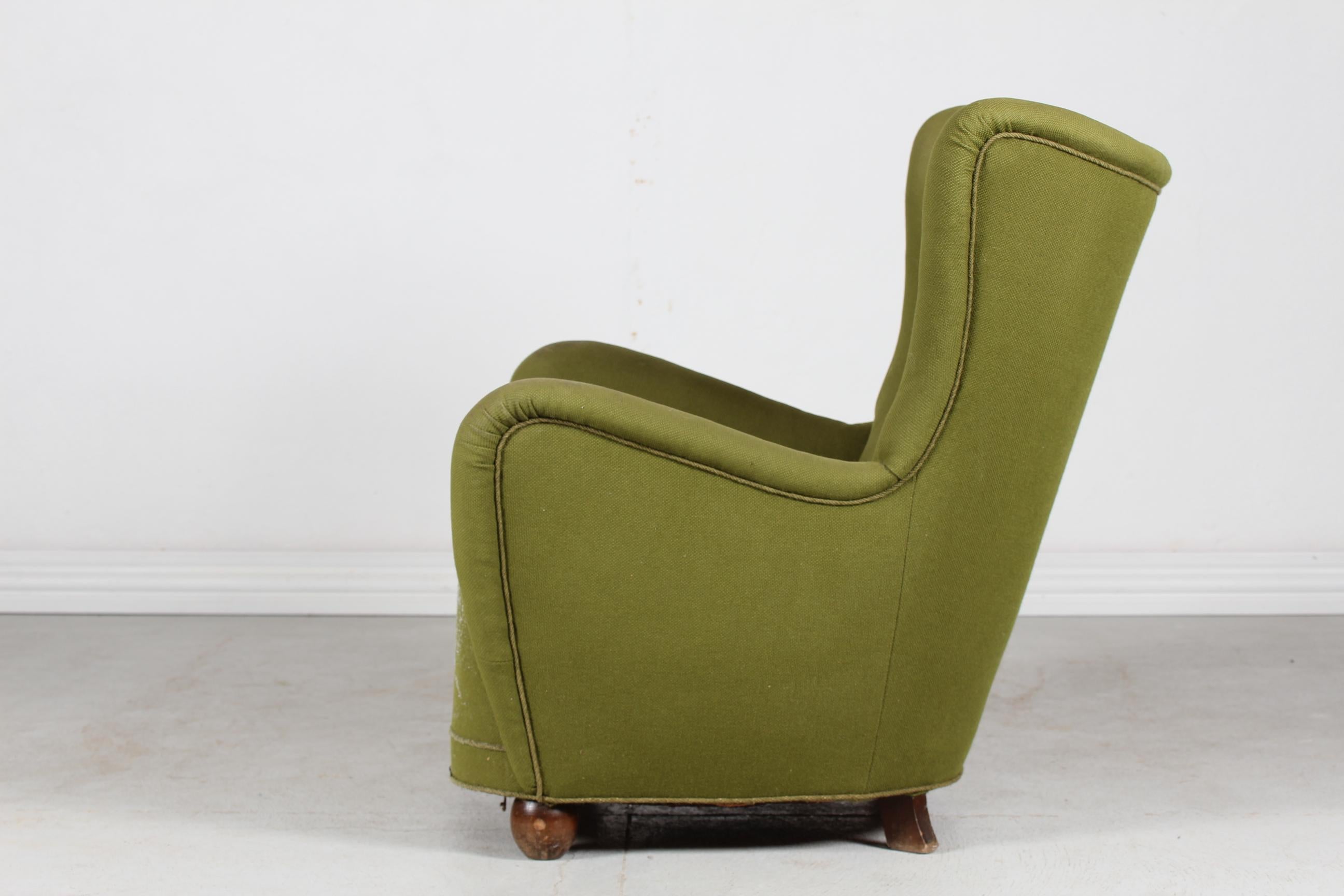 Large authentic Art Deco lounge chair from the 1940's with ball shaped front feet. The feet are made of dark stained beech wood and the comfortable chair is upholstered with dusty green fabric. 
Made by Danish cabinet maker in the 1940s in Fritz