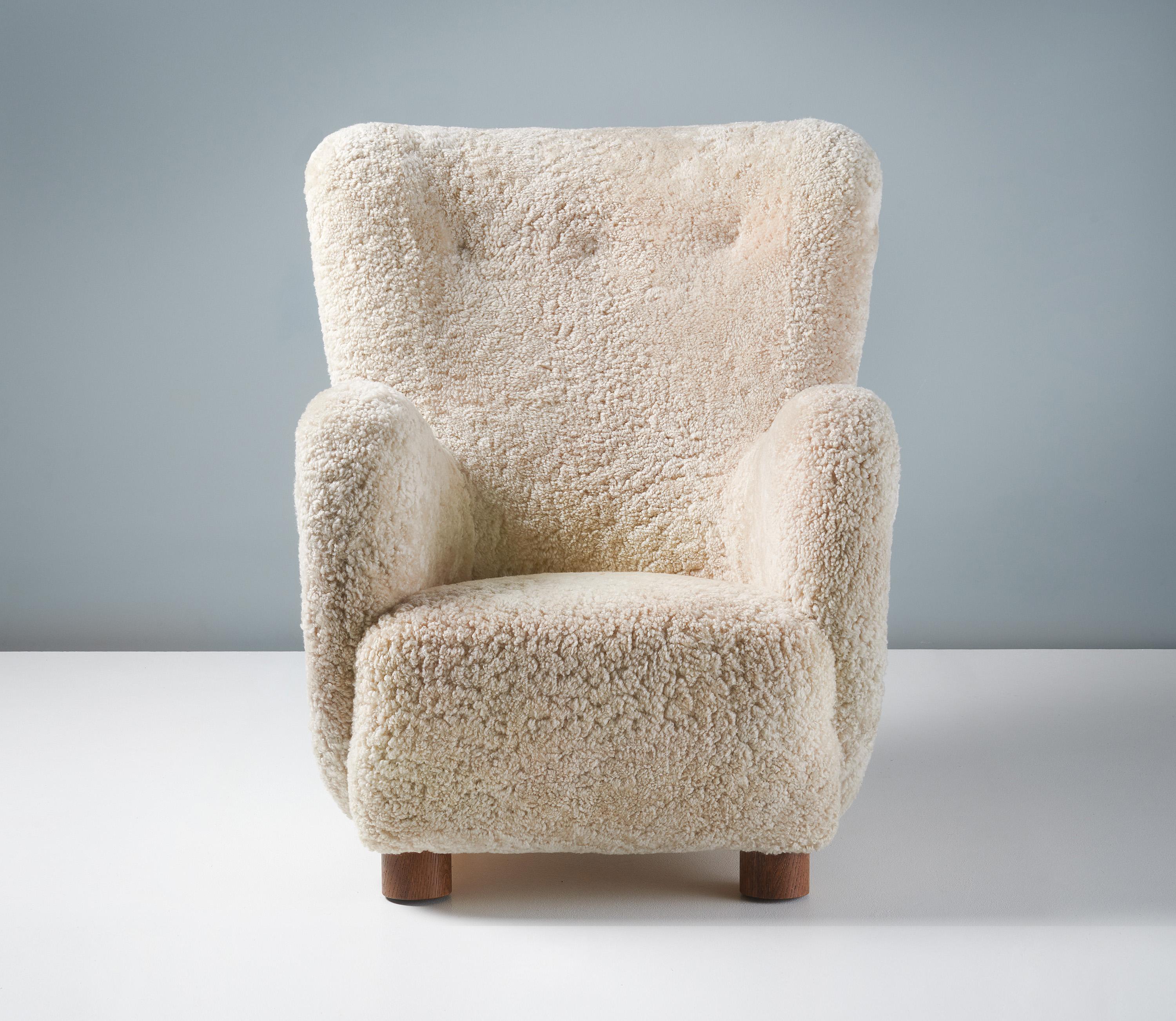 Danish Cabinetmaker Sheepskin Armchair, circa 1940s.

This tall lounge chair produced by a Danish Cabinetmaker in the 1940s is typical of Danish lounge chair designs of the day. It features a slightly curved wing-back with large round arms and