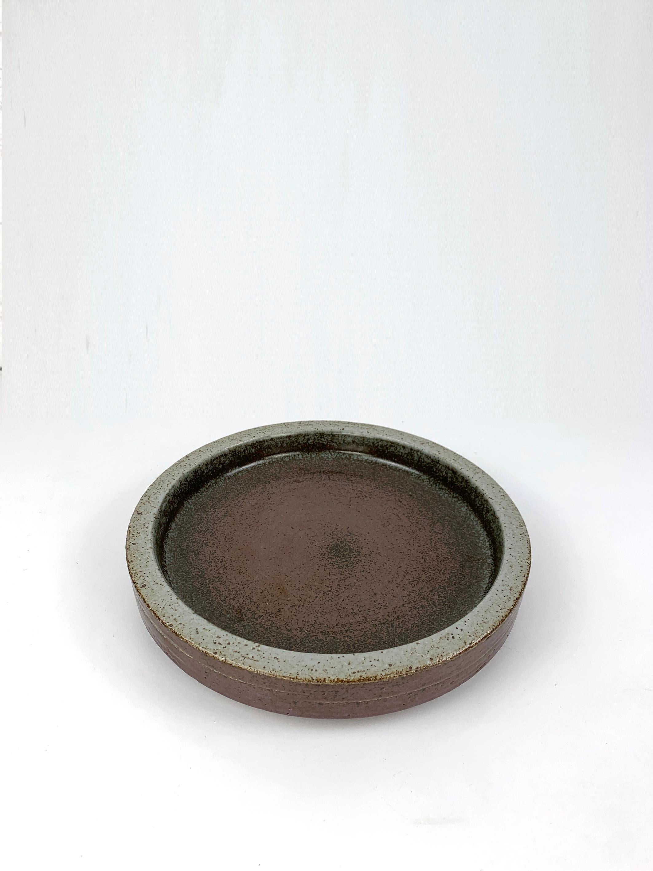 Large round ceramic vide-poche or low bowl in earth tones beige-grey brown. 

Scandinavian Mid-Century 1960s, produced by Palshus (Denmark), founded by Per and his wife Annelise Linnemann-Schmidt. 

The couple created and produced chamotte (danish