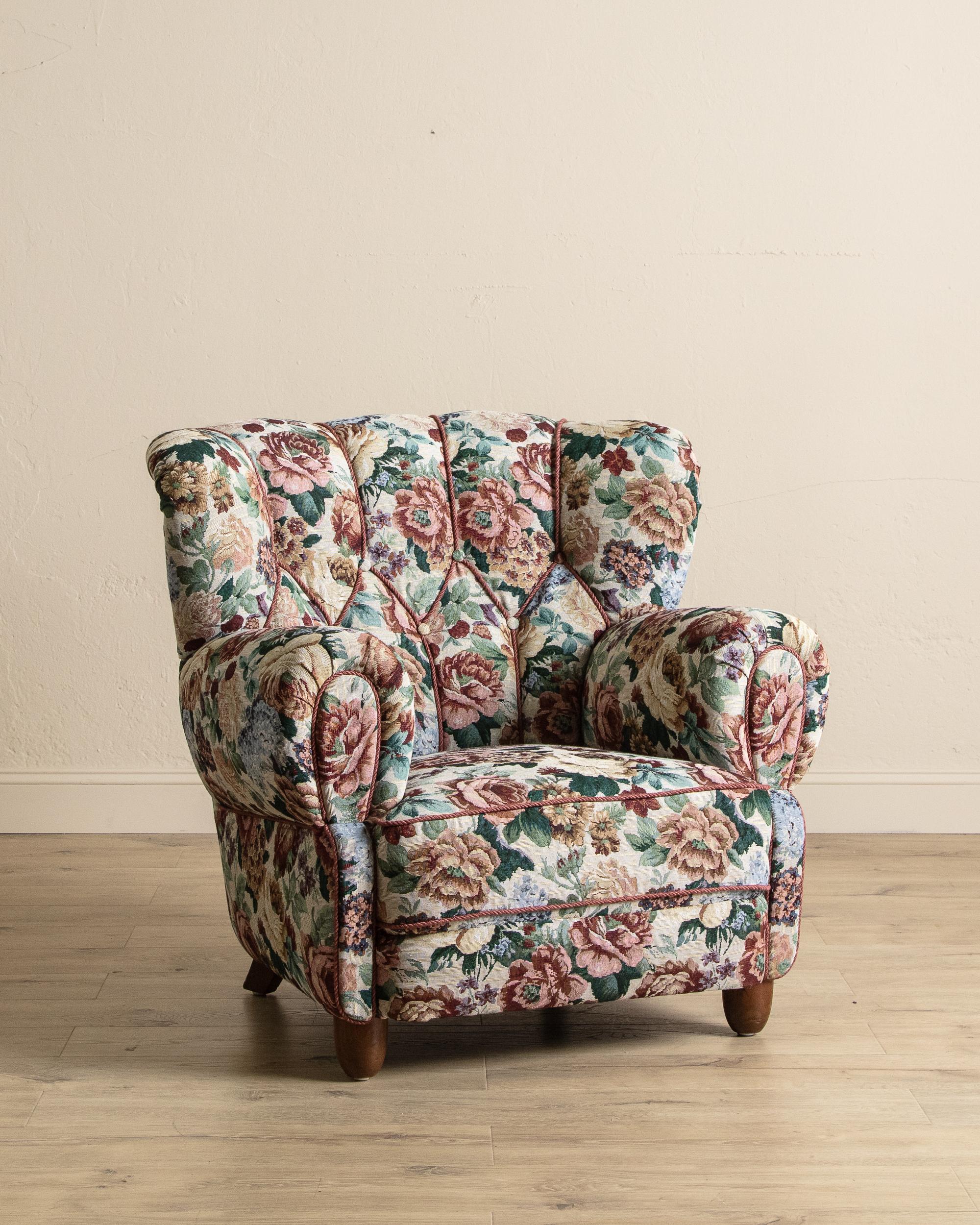 This large Danish club chair from the 1940s exudes vintage romance and refined craftsmanship, newly restored to highlight its sculptural form. Professionally reupholstered in a richly patterned floral tapestry with coordinating rope trim, the chair