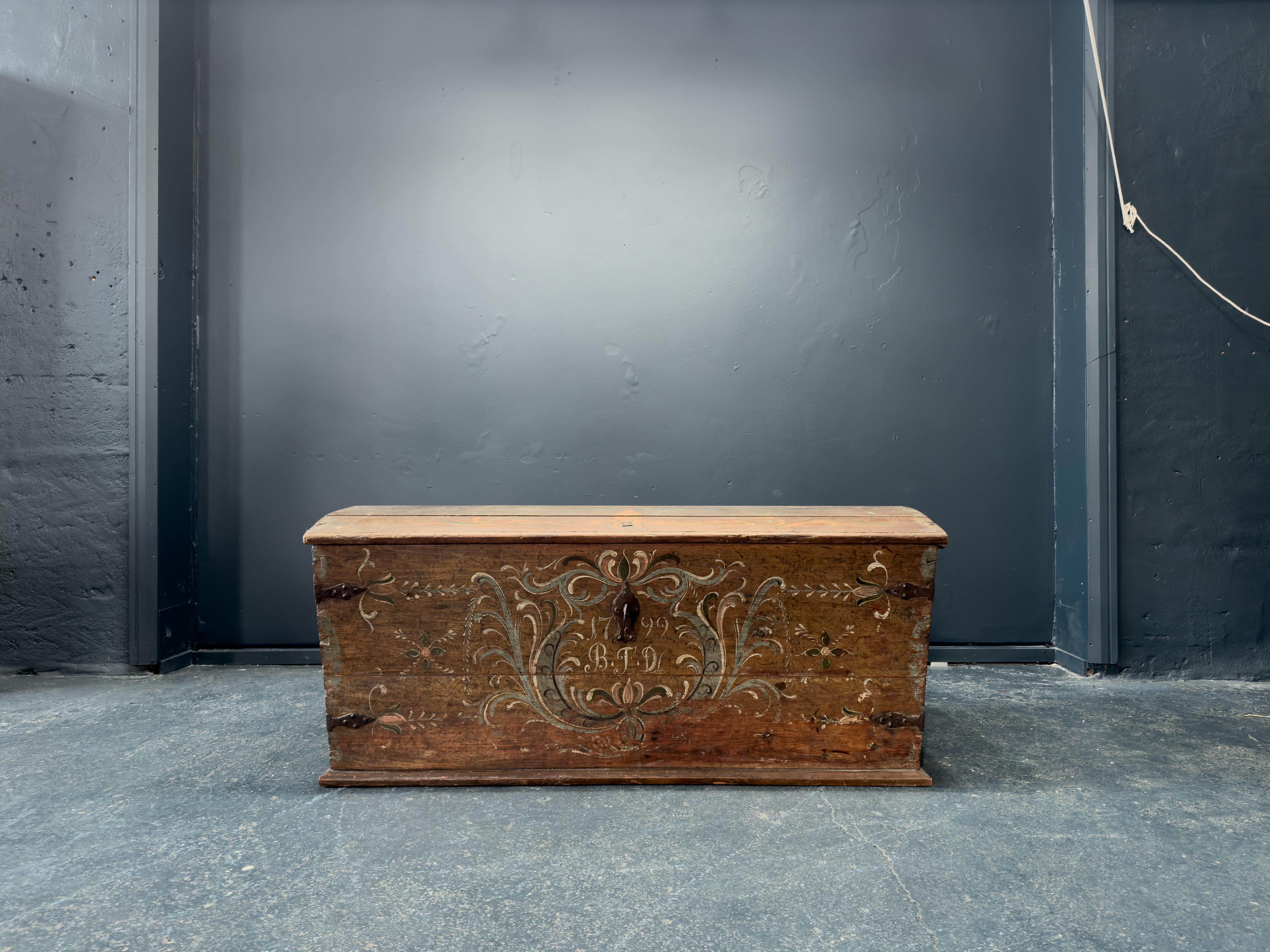 Cette magnifique pièce folklorique historique est un exemple de l'excellence de l'artisanat danois qui résiste à l'épreuve du temps. Ce coffre date du XVIIIe siècle, avec un superbe motif peint à la main datant de 1799. Avec sa quincaillerie en fer