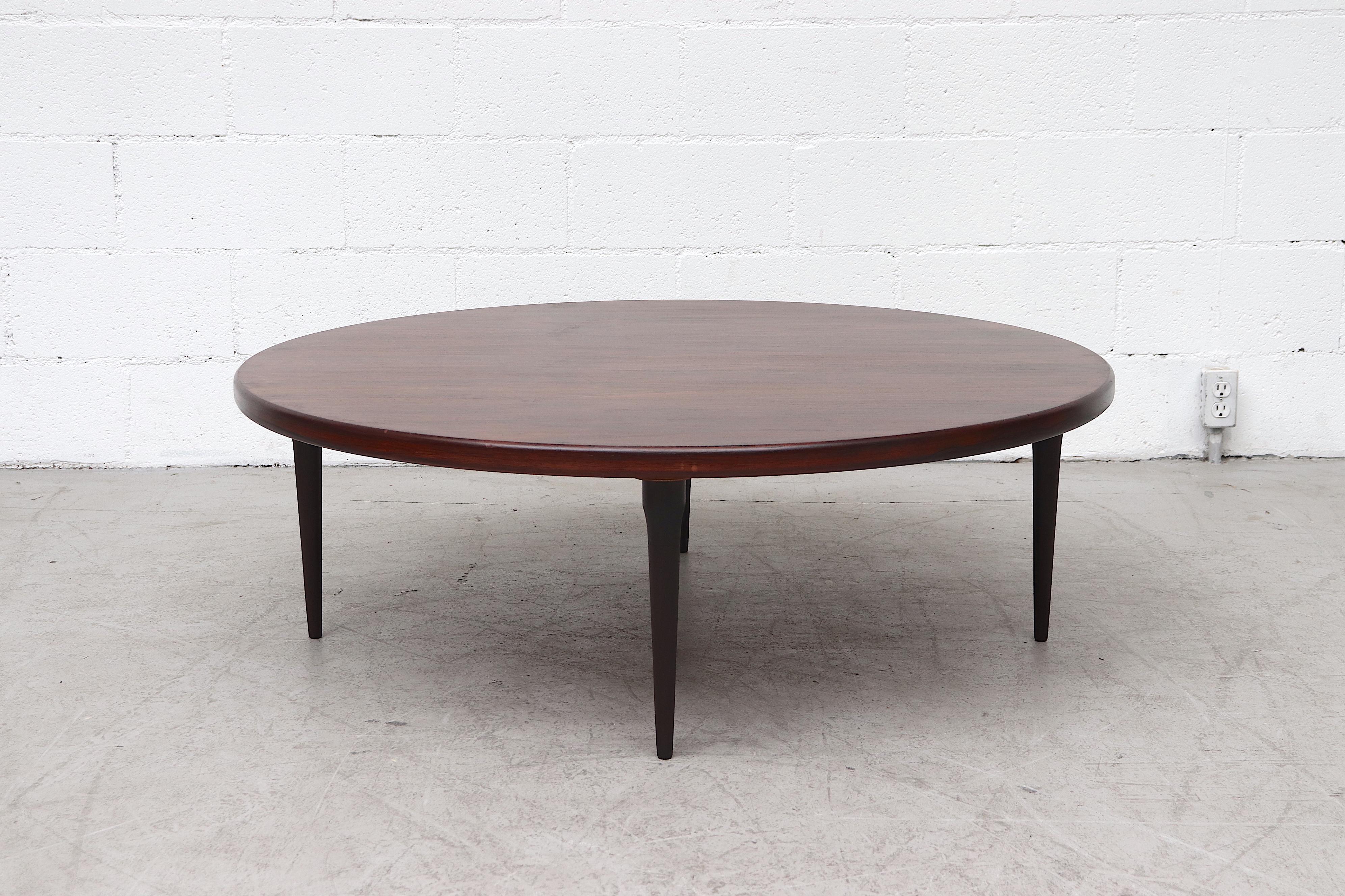 Gorgeous large round Mid-Century rosewood coffee table lightly refinished with beautiful grain pattern and tapered wood legs. In original condition with light wear and scratching consistent with age and use.