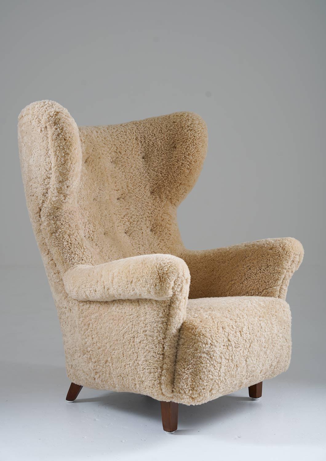 Sculptural high back wing chair manufactured in Denmark, circa 1940. 
This majestic chair looks great from any angle with its harmonic expressions. On top of that, it is as comfortable as it looks. It's been upholstered in honey-white sheepskin and