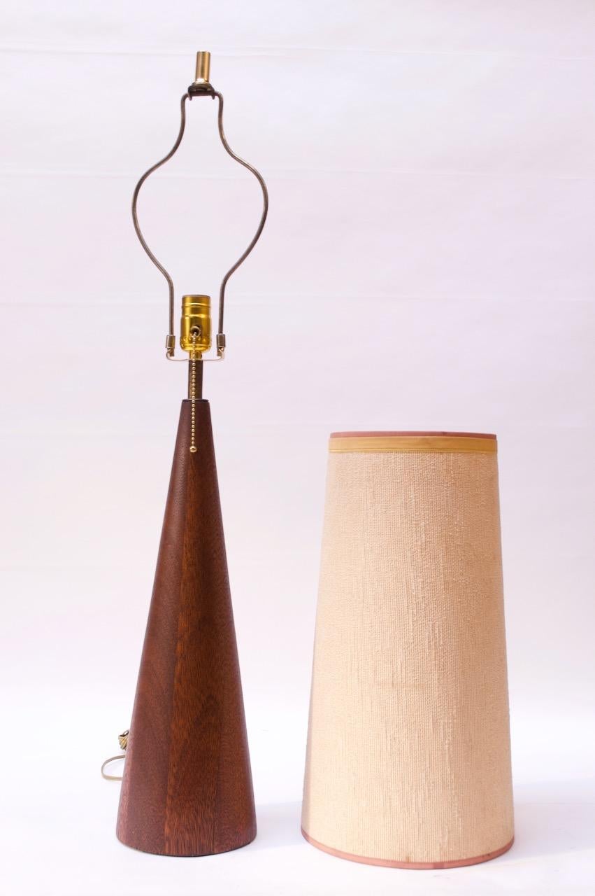 Substantial Danish table lamp paired with a vintage cylindrical, shade (circa 1960s).
Vivid teak grain and sculptural conical form. Teak has been newly refinished, only light wear remains. Brass stem boasts natural patina and has not been polished.