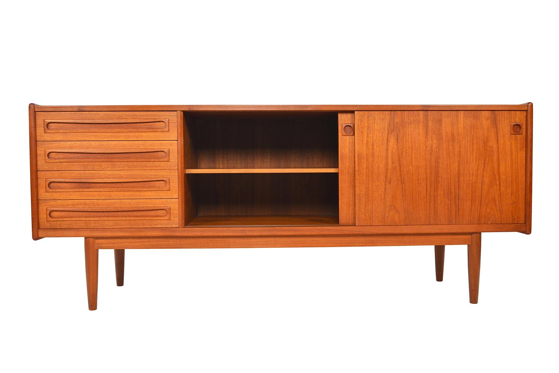 This beautiful Danish modern midcentury teak credenza by Jensen + Molholm offers a wonderfully functional configuration for modern living! Executed with clean lines and Minimalist details, center and right doors slide open to reveal adjustable