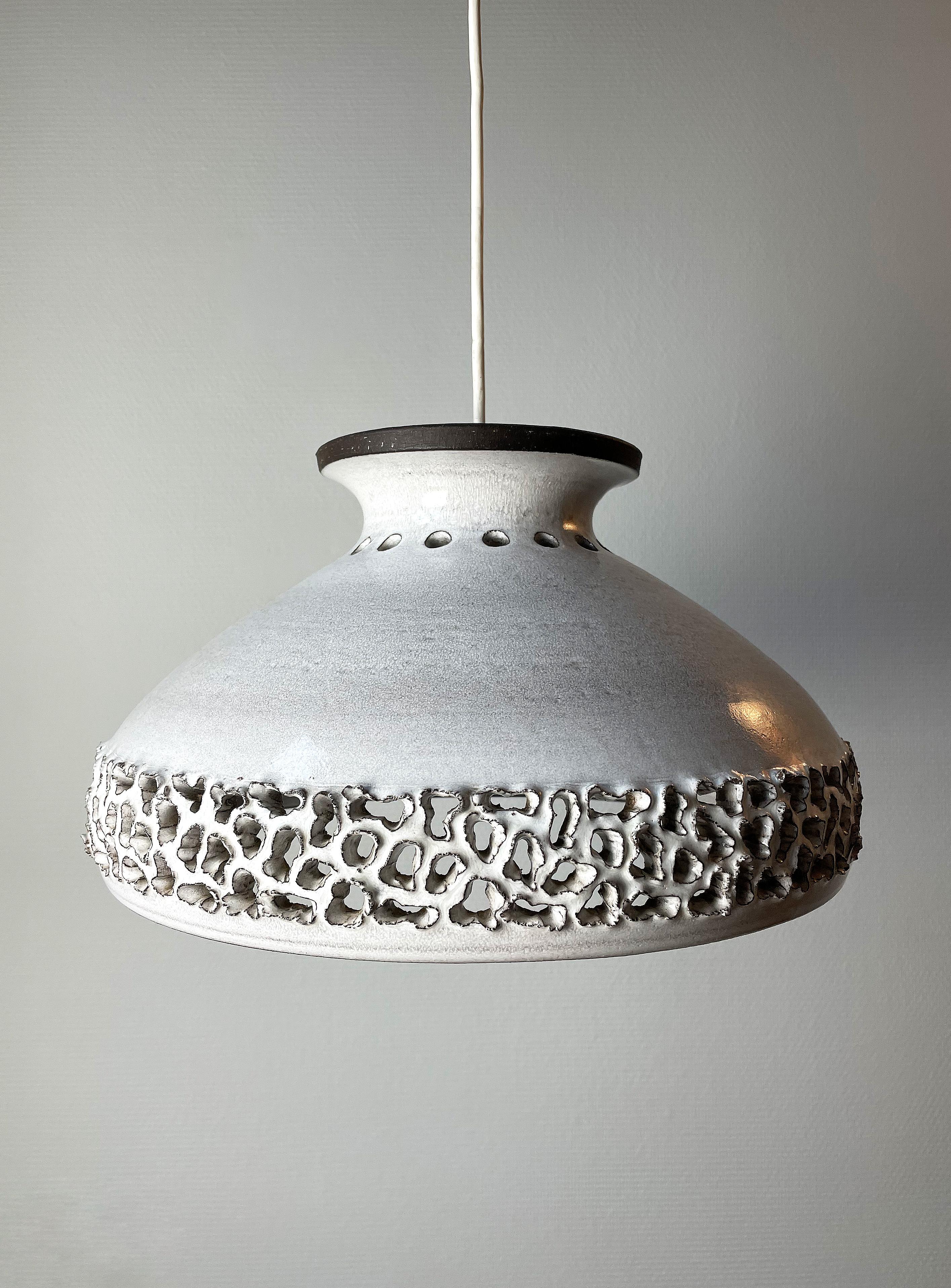 Large, stunning, open base, handmade ceramic pendant. Rustic perforations showcasing the ceramic material and letting the light out around the base. Circle perforations around and on the top. Light grey glaze with unglazed dark brown accents.