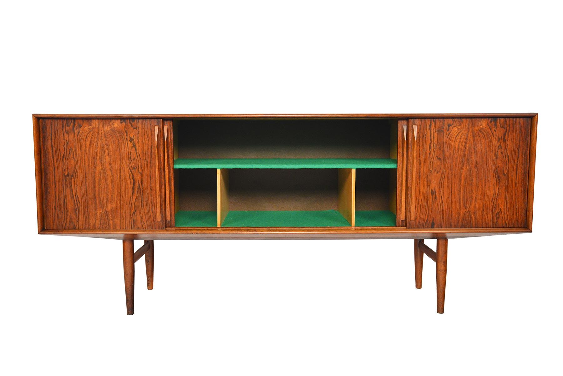 Beautifully crafted in Brazilian rosewood, this large credenza was designed by Kurt Østerving for KP Mobler in the 1960s. Four sliding doors open to reveal three bays. The left bay is outfitted with five drawers, the center bay offers fixed